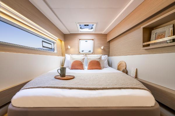 Luxurious cabin interior of 2025 Lagoon 43 yacht with cozy bed and modern decor.