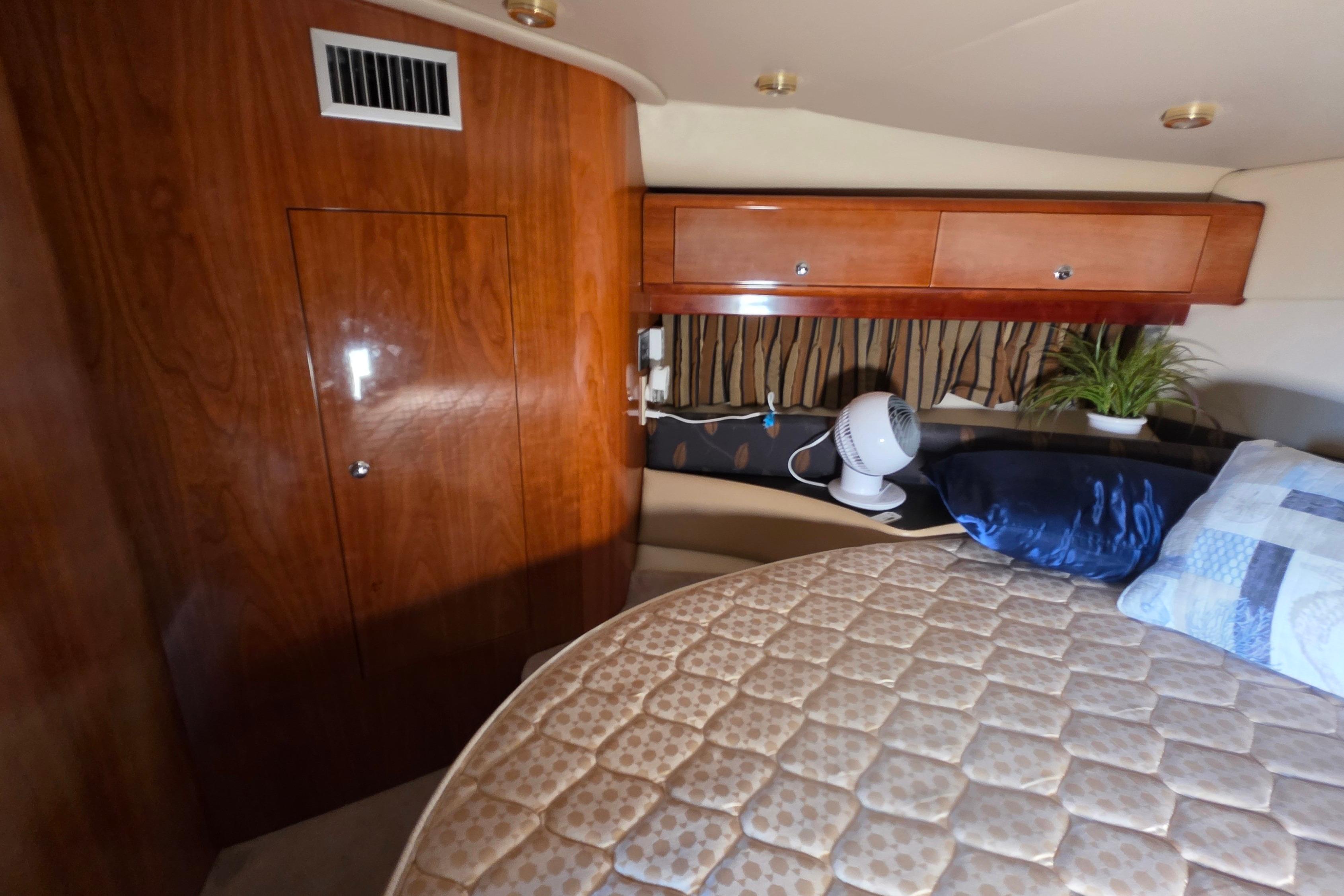 Interior cabin of 2002 Regal Commodore 4260 yacht with wood paneling and cozy bedding.