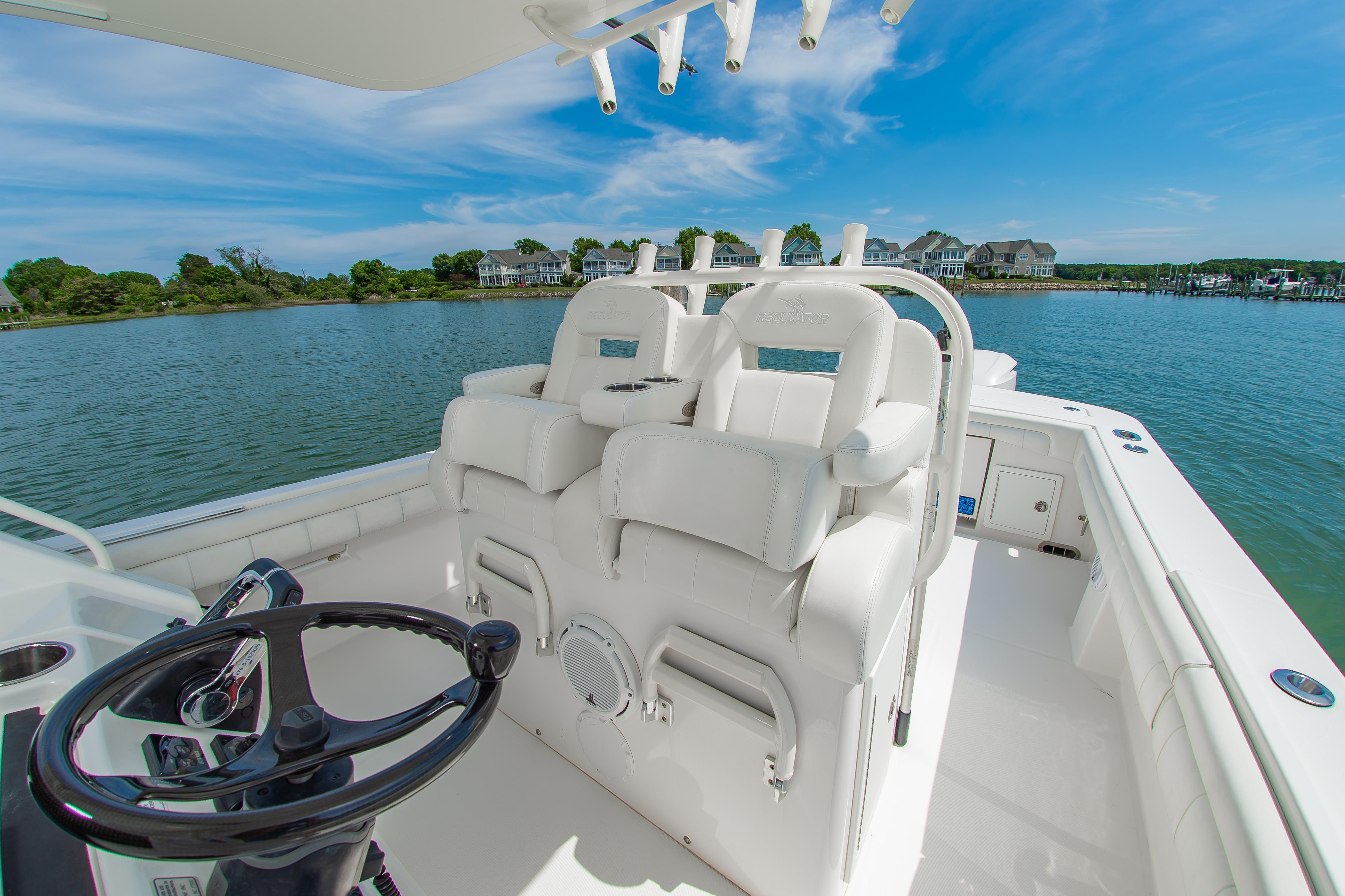 2019 Regulator 31 boat interior with helm and seating, overlooking serene waterfront homes.