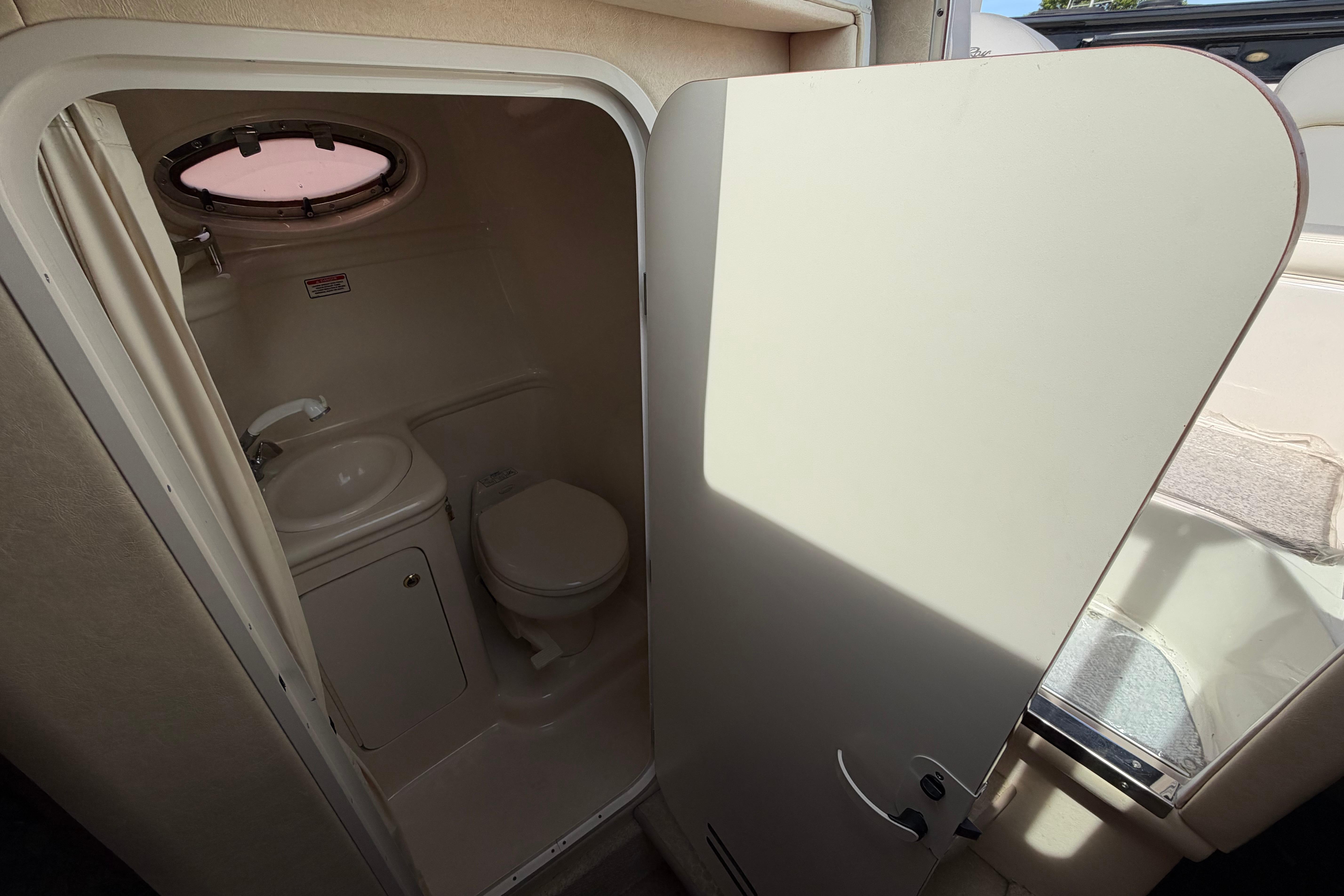 Compact bathroom in 2004 Sea Ray Sundancer 260 boat, featuring sink and toilet.
