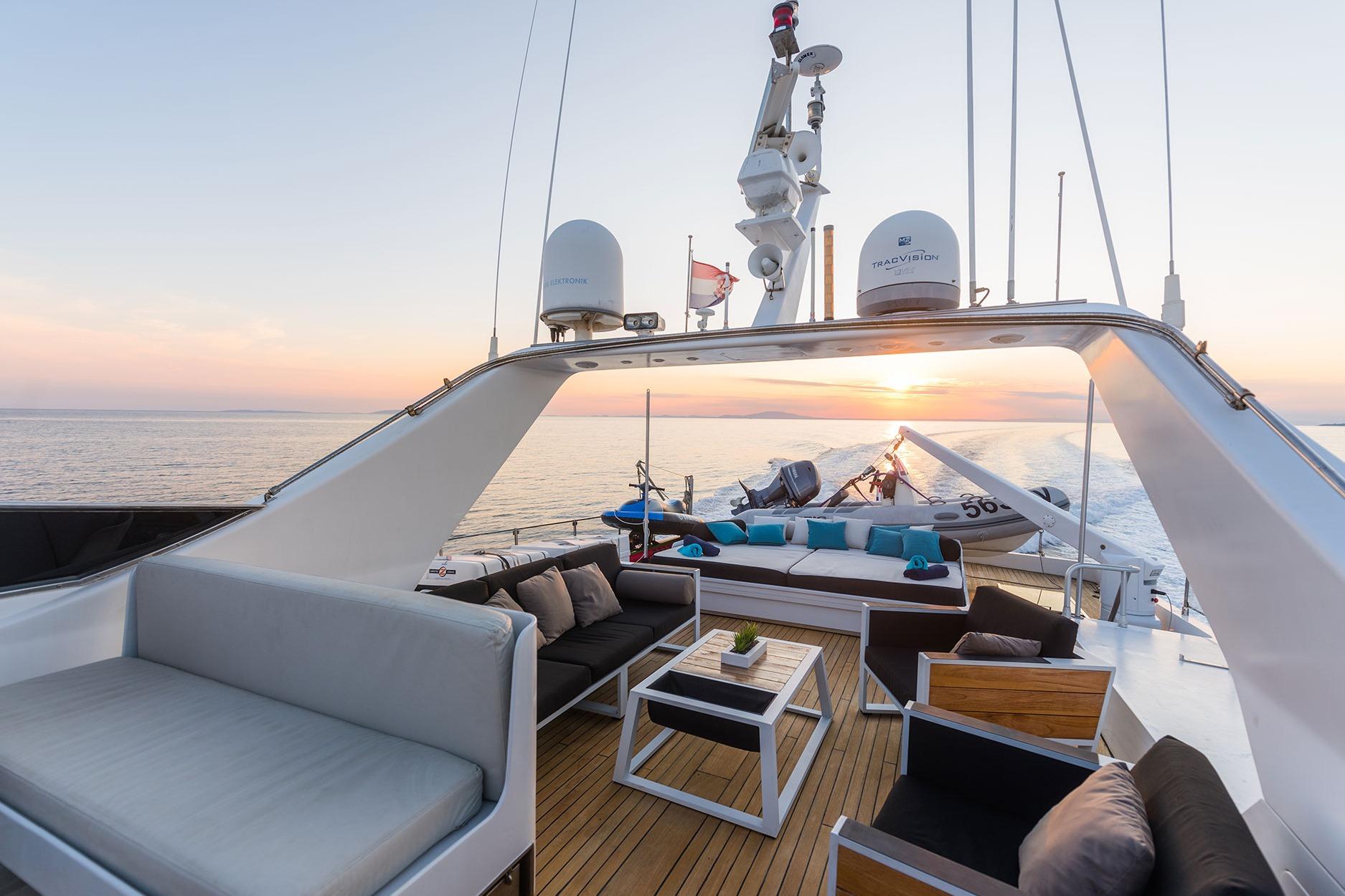Luxurious Admiral 27m yacht deck at sunset, featuring elegant seating and ocean views.