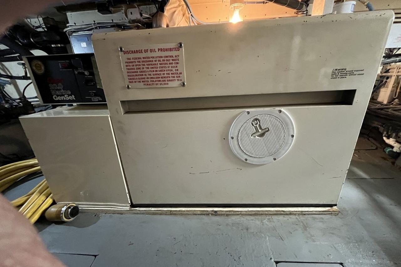 Engine room of 1991 Hatteras 61 Motor Yacht with generator and warning sign.