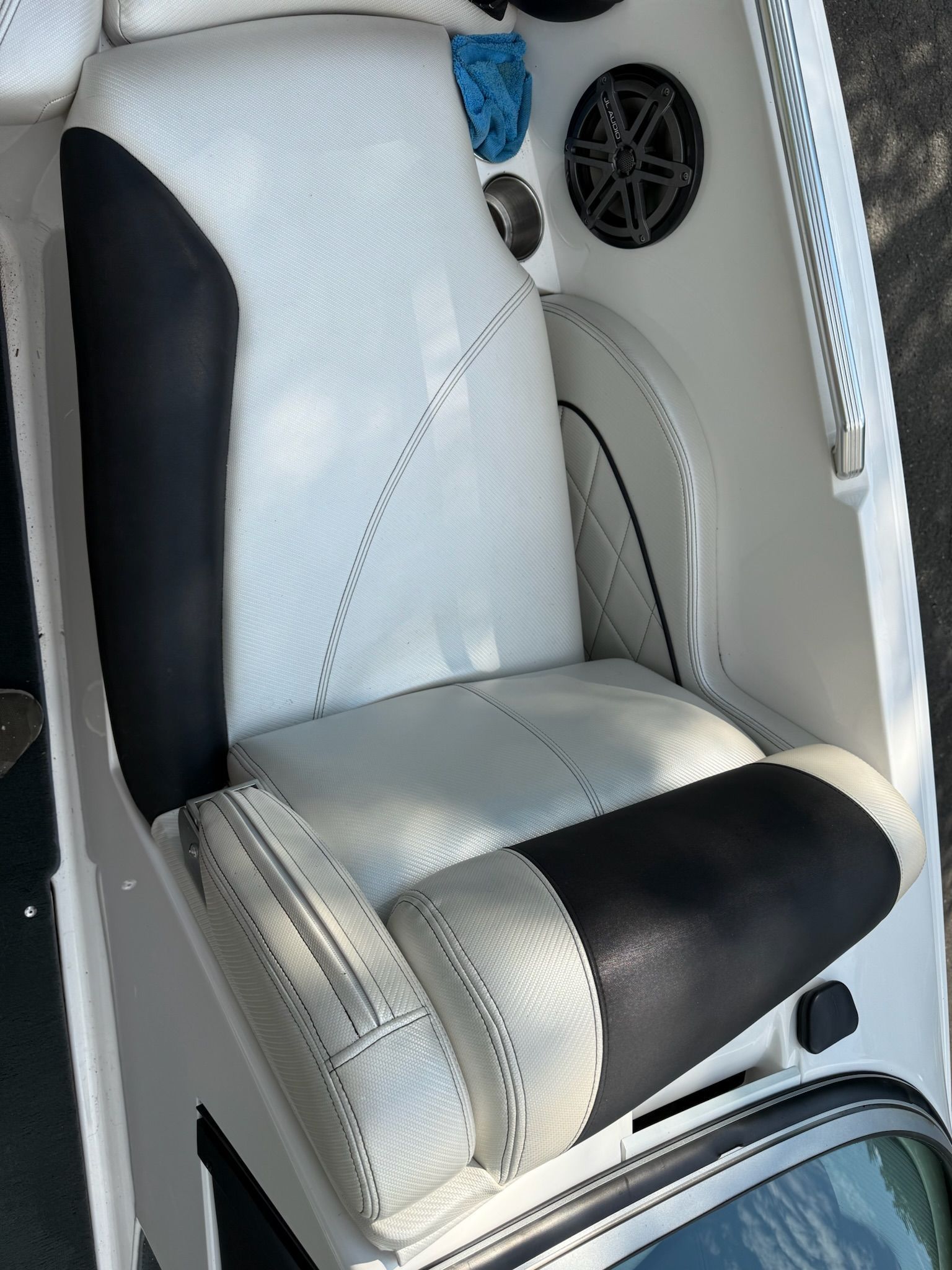The image shows a white and black seat in a boat with a speaker and cup holder.