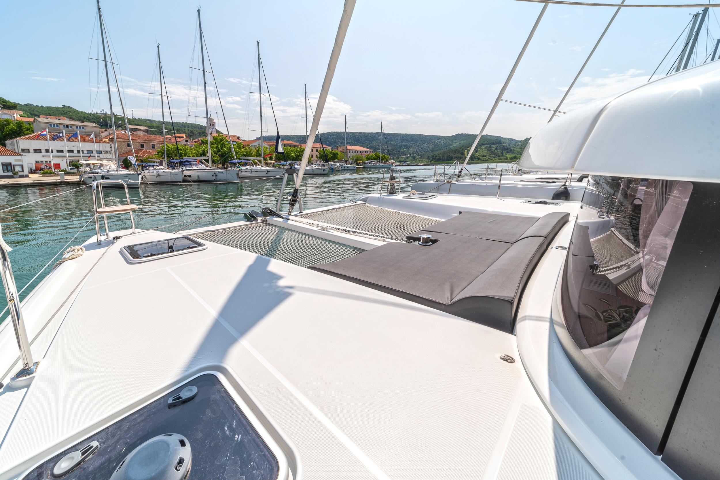 2023 Lagoon 42 catamaran docked in a scenic marina with clear skies.