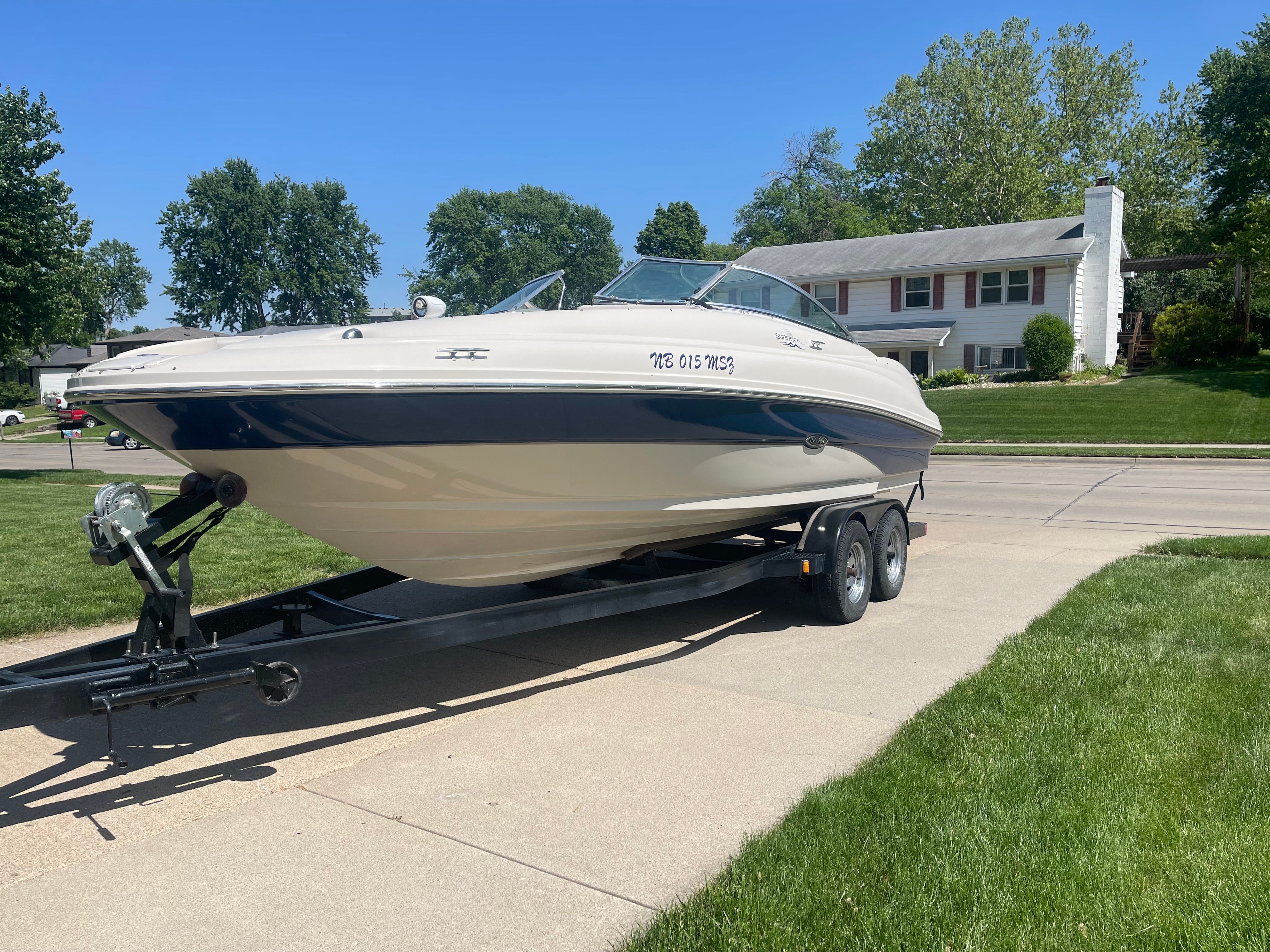 A Sea Ray 220 Sundeck boat on a trailer in a residential area.