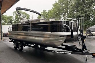 2026 Sun Tracker Fishin' Barge 20 DLX pontoon boat on trailer, parked outdoors.