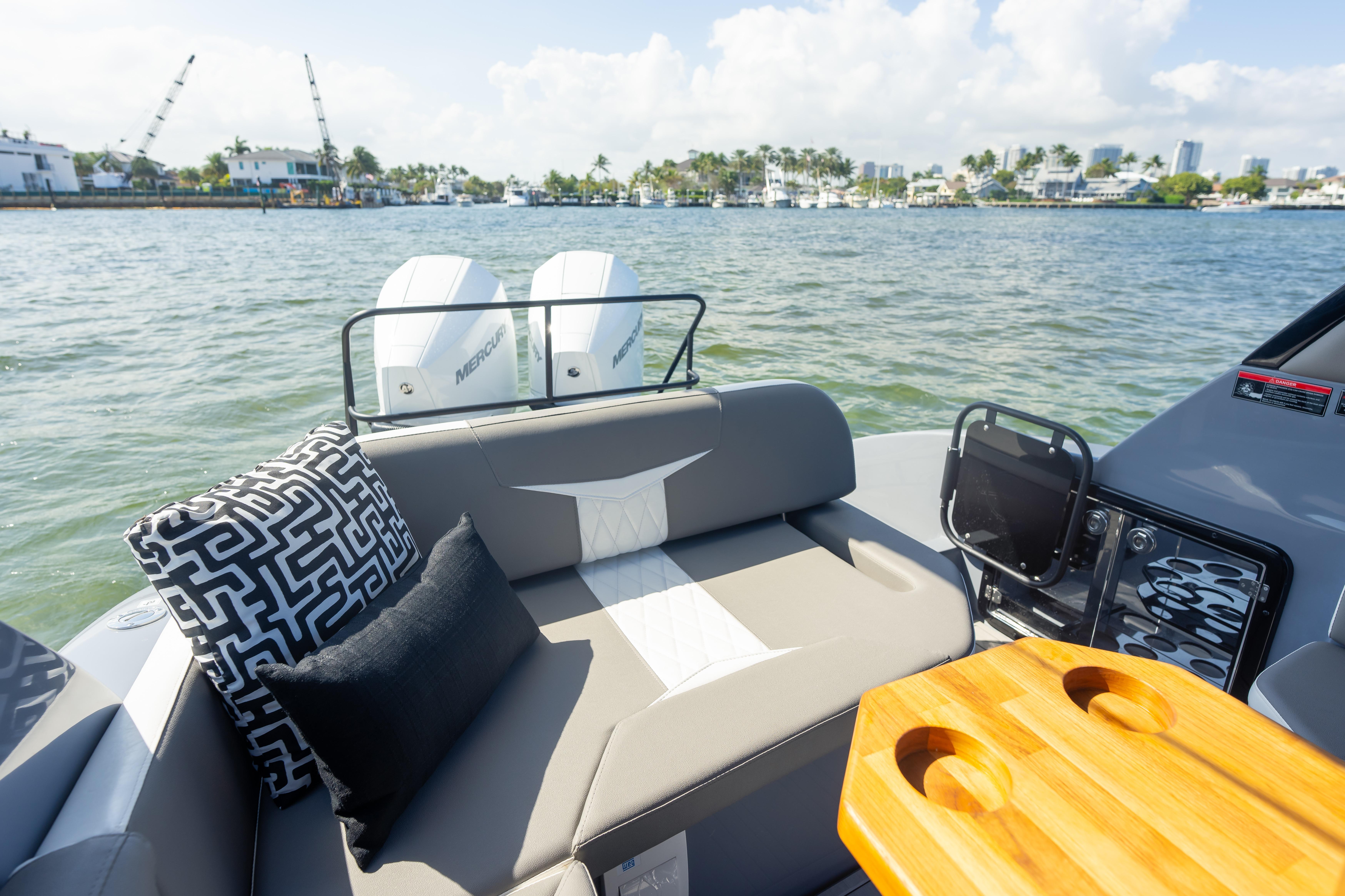 Luxurious Hanover 305 boat interior with cushions, table, and twin engines on a sunny day.