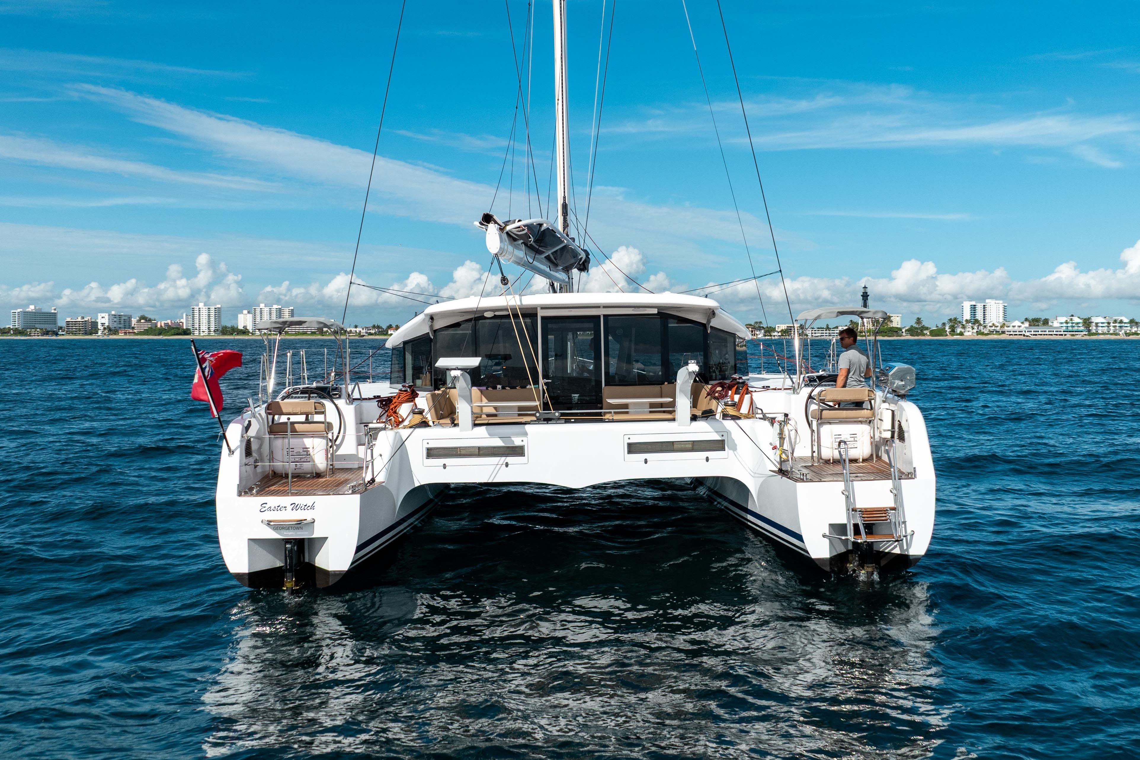 Ocean Explorer Catamaran sailing near coastal city under clear blue sky.
