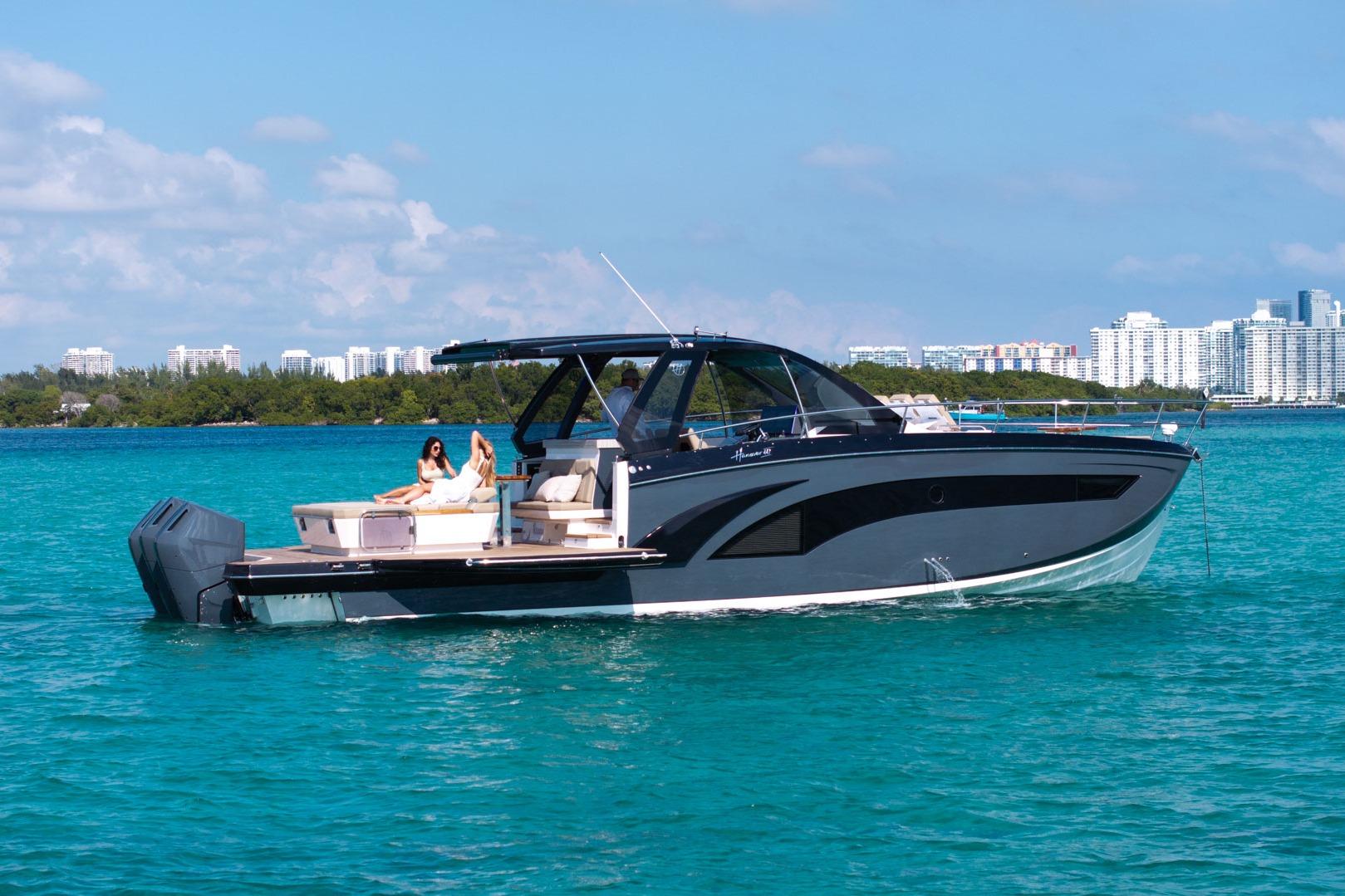 Luxurious 2026 Hanover 447 yacht cruising on turquoise waters near a city skyline.