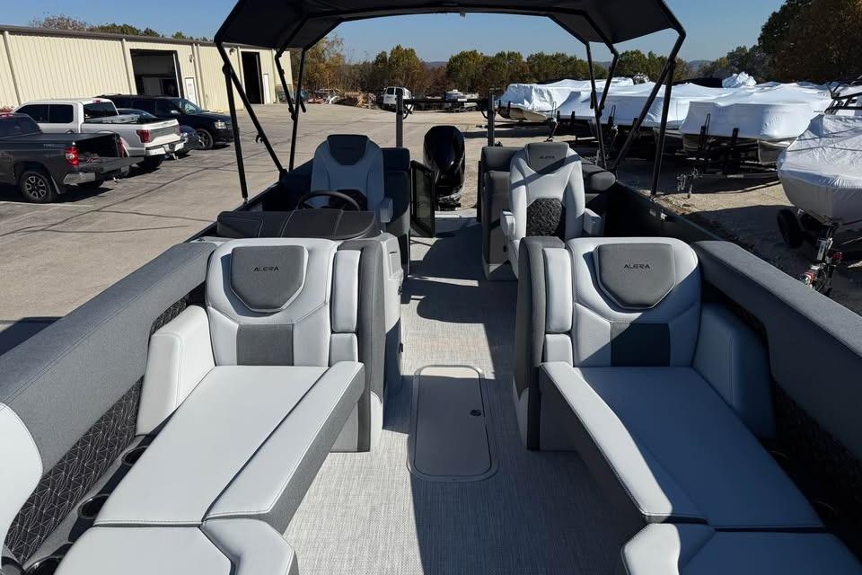 2026 Alera M 25Q boat interior with modern seating and canopy in a marina setting.