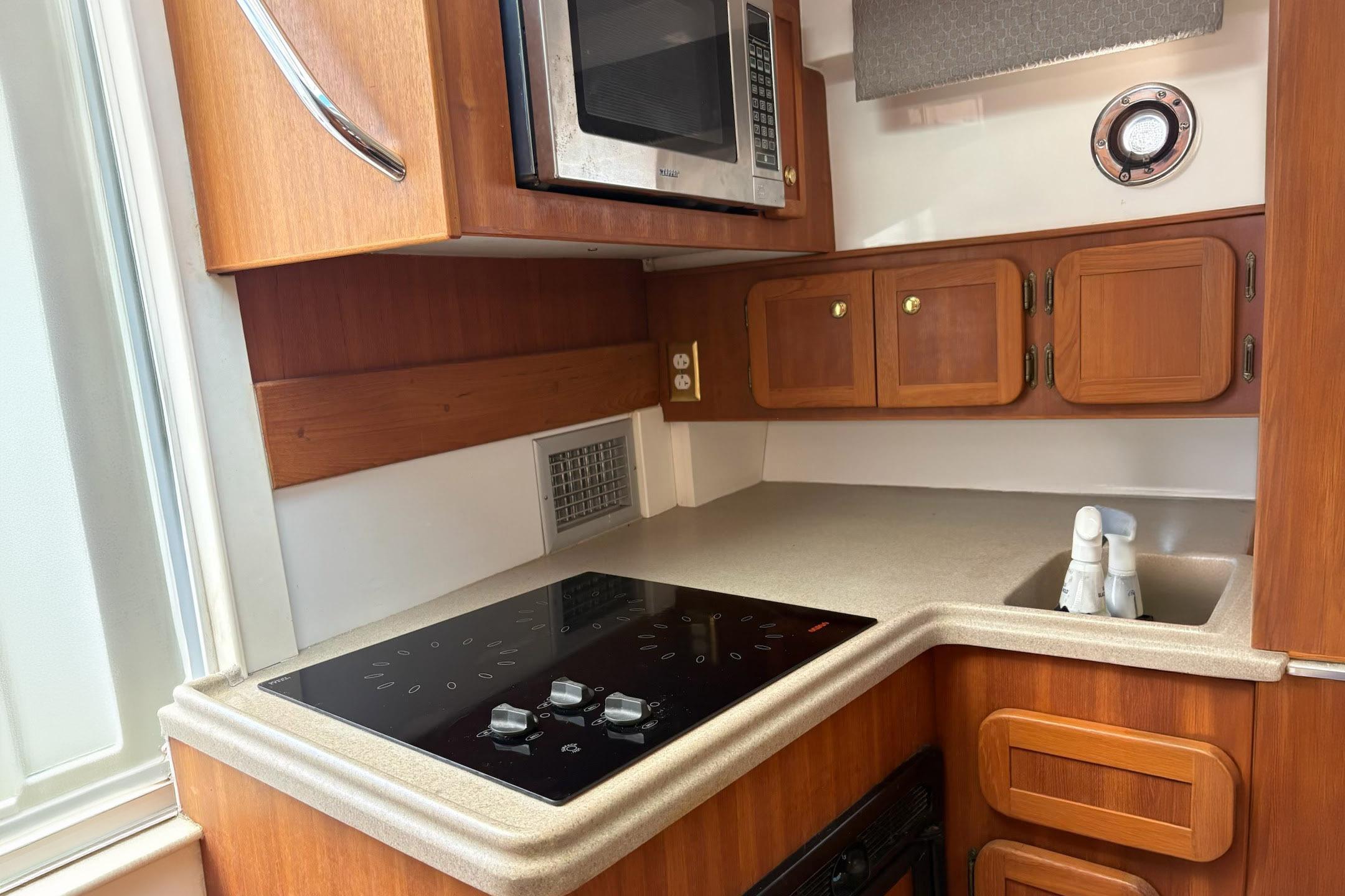 2008 Stamas 370 Express yacht kitchen with wooden cabinets, stove, and microwave.