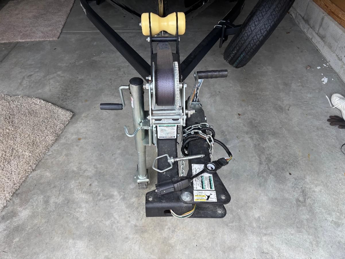 Close-up of a boat trailer with a winch and support wheel.