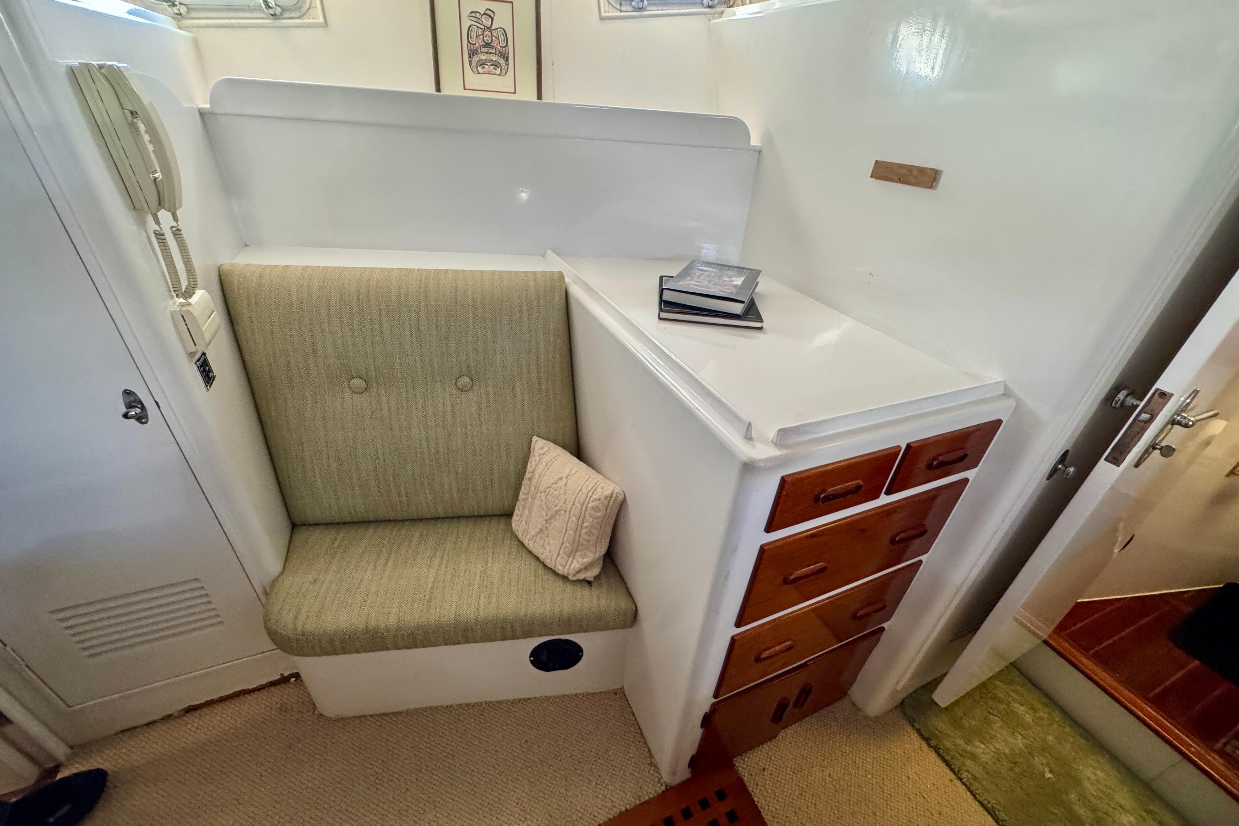 1958 Blanchard Pilothouse interior with cushioned seat, wooden drawers, and nautical decor.