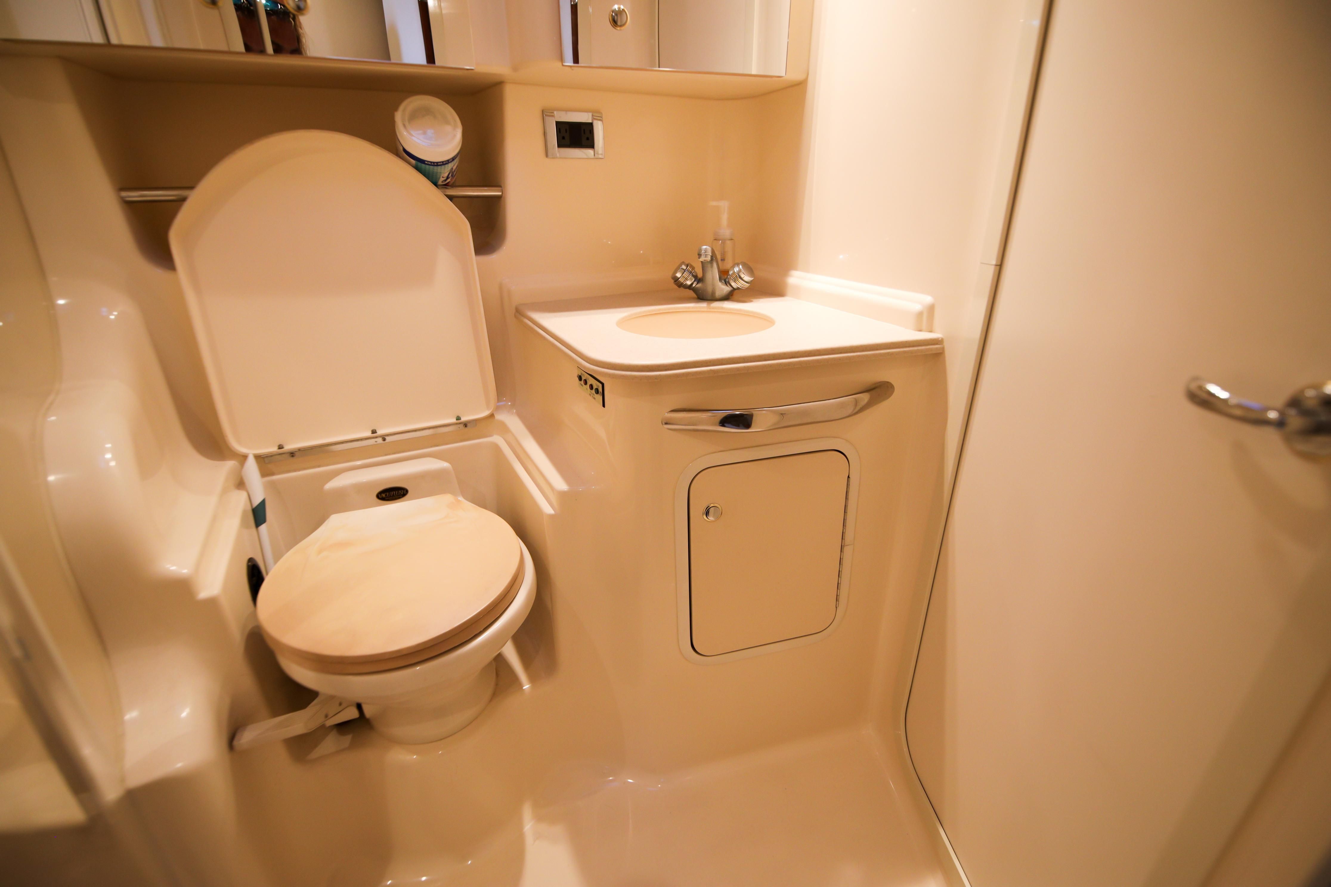 Bathroom with toilet and sink in a boat, beige interior, compact and functional.