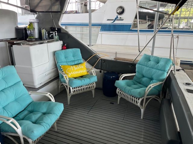 The image shows a boat seating area with blue cushions and a "Hello Summer" pillow.