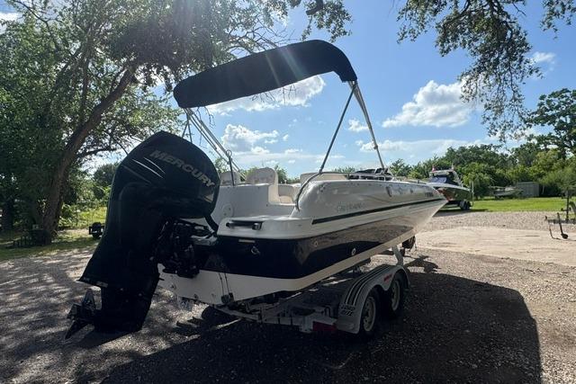 1999 Hurricane SunDeck Sport 201 OB boat on trailer, parked outdoors under trees.