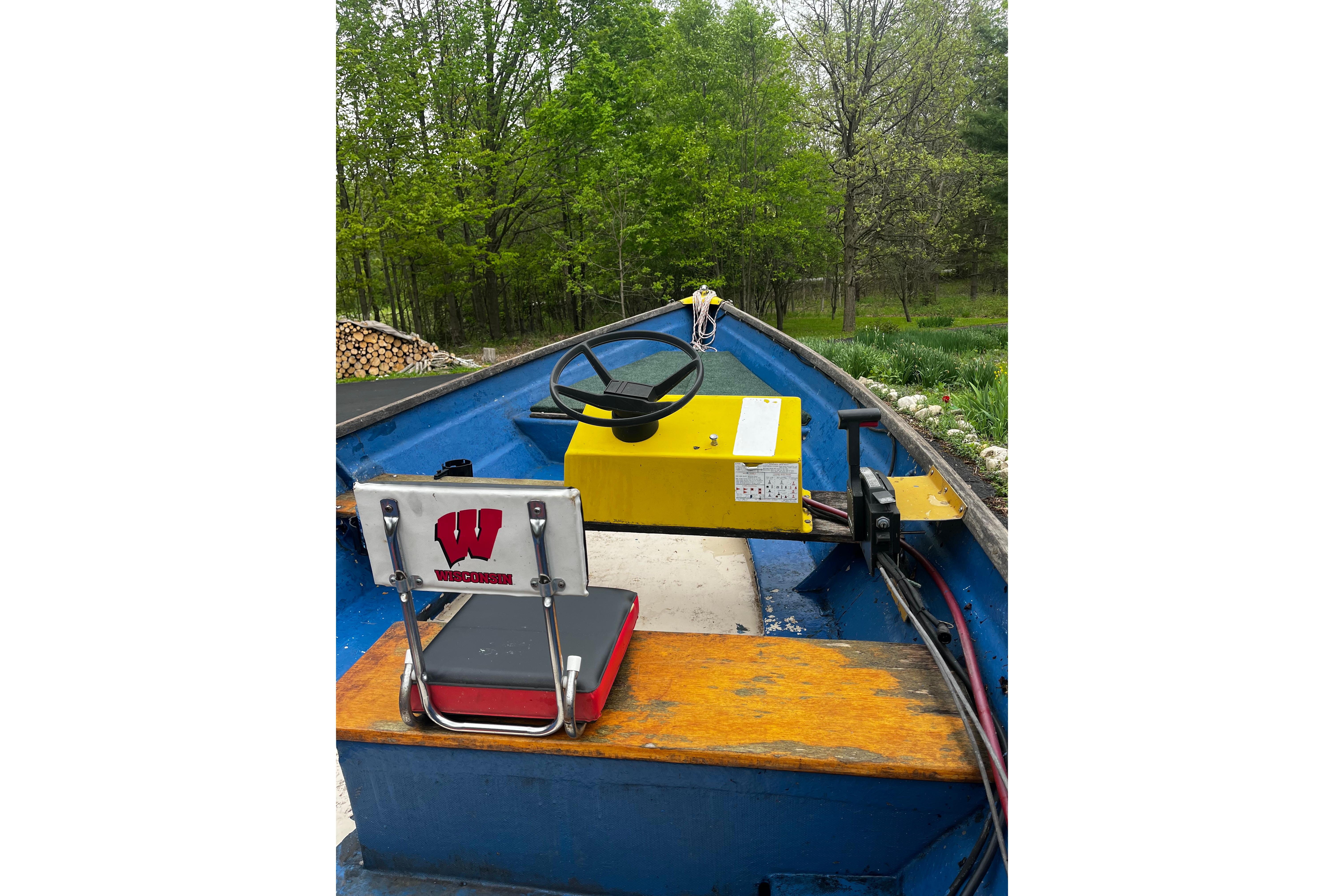 1968 Cape Dory John Dory Center Console boat with Wisconsin-themed seat, surrounded by lush greenery.
