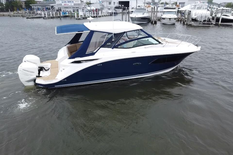 2021 Sea Ray Sundancer 320 Outboard cruising in a marina, featuring sleek design and powerful engines.