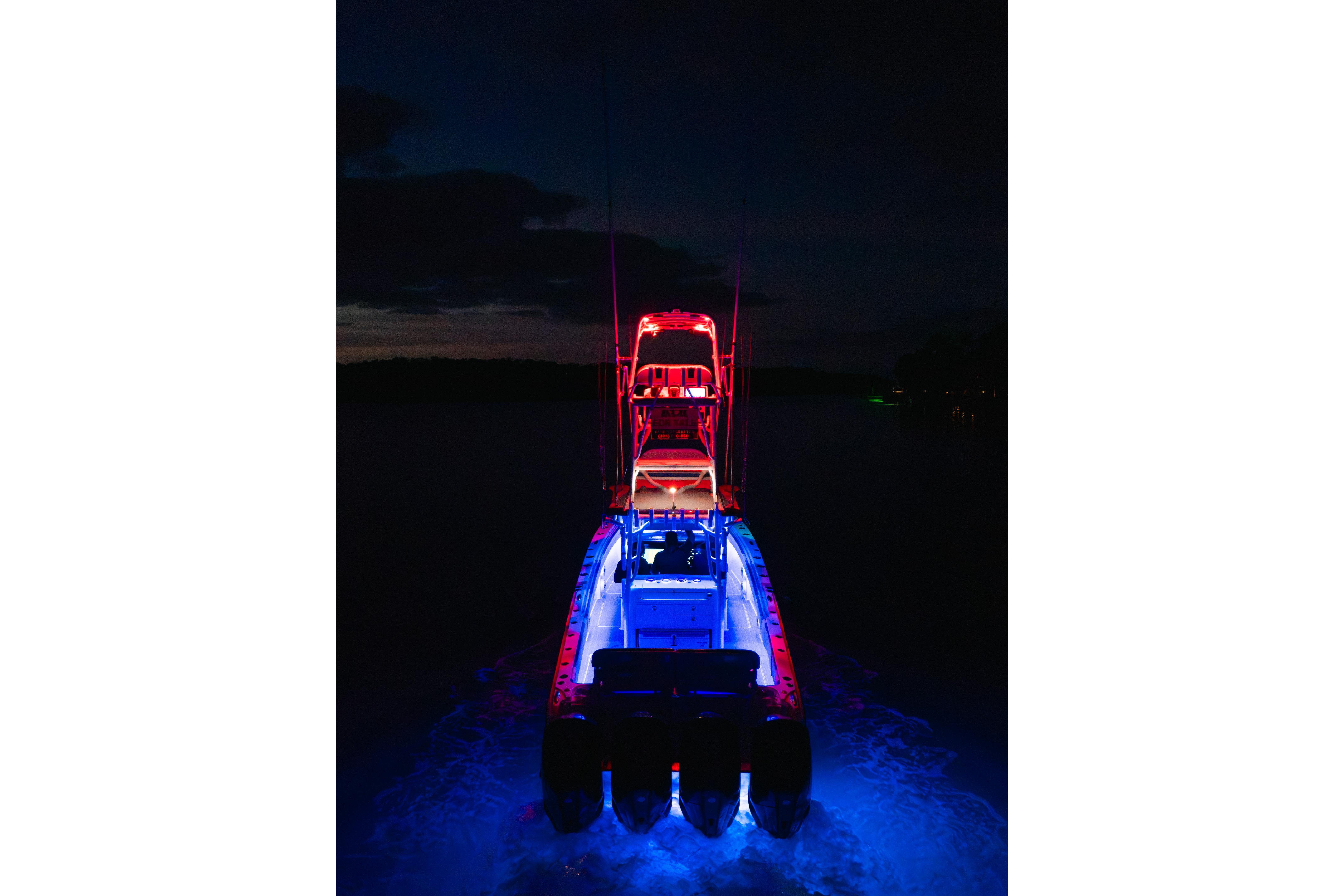 Nor-Tech 392 Super Fish 2022 boat illuminated with vibrant red and blue lights at night.