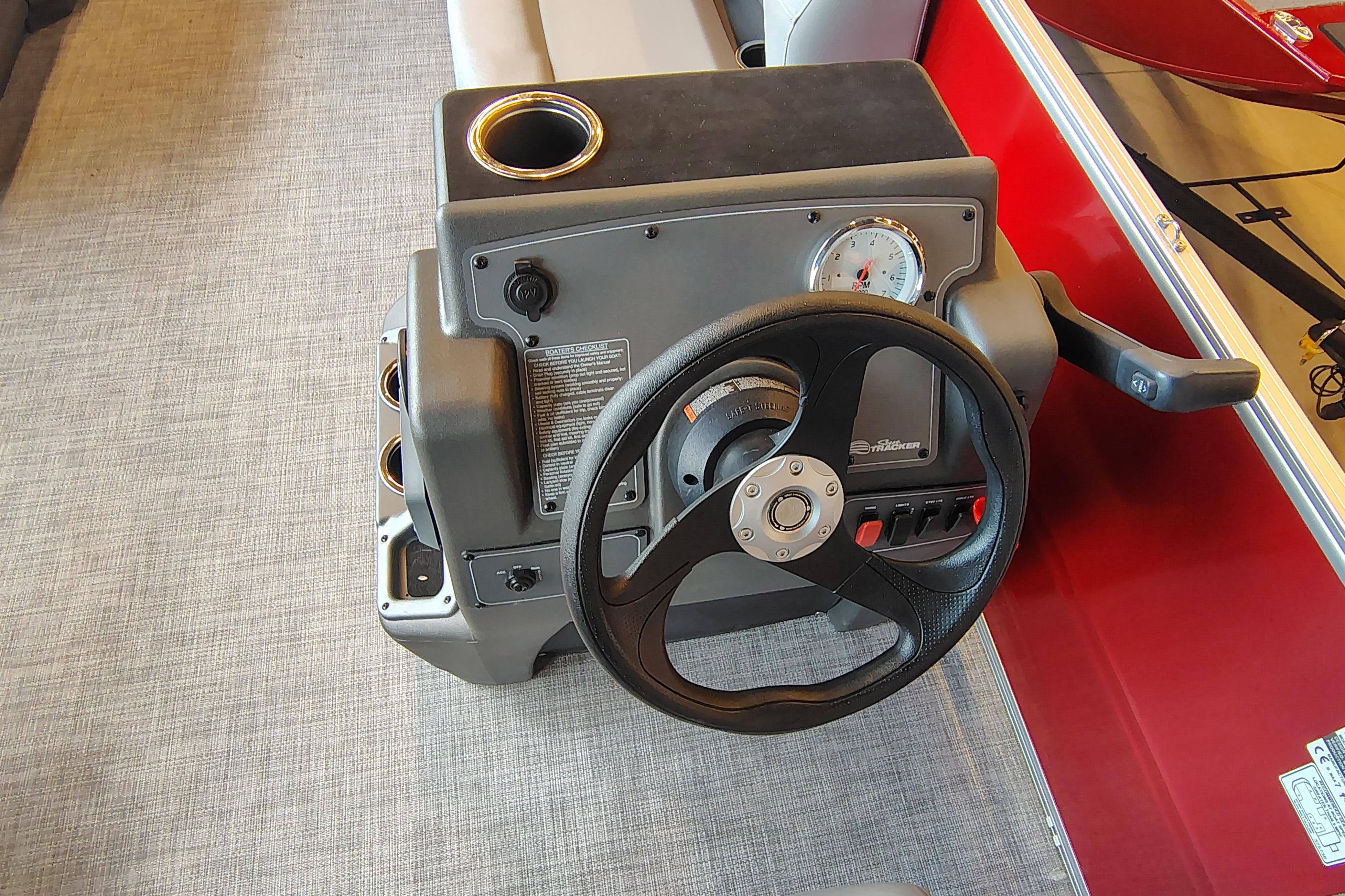 Steering console of 2026 Sun Tracker Party Barge 16 DLX with cup holder and controls.
