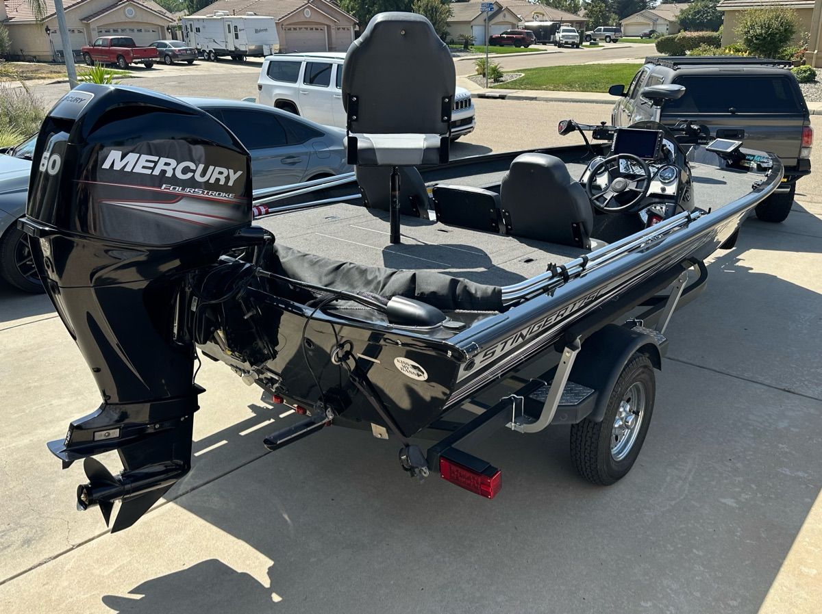A black 2018 Lowe Stinger 175C boat on a trailer in a residential area.