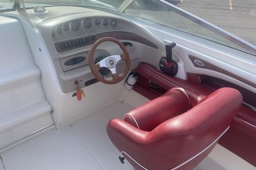 Interior view of a 1997 Sea Ray 230 Overnighter boat with red seating and wooden steering wheel.