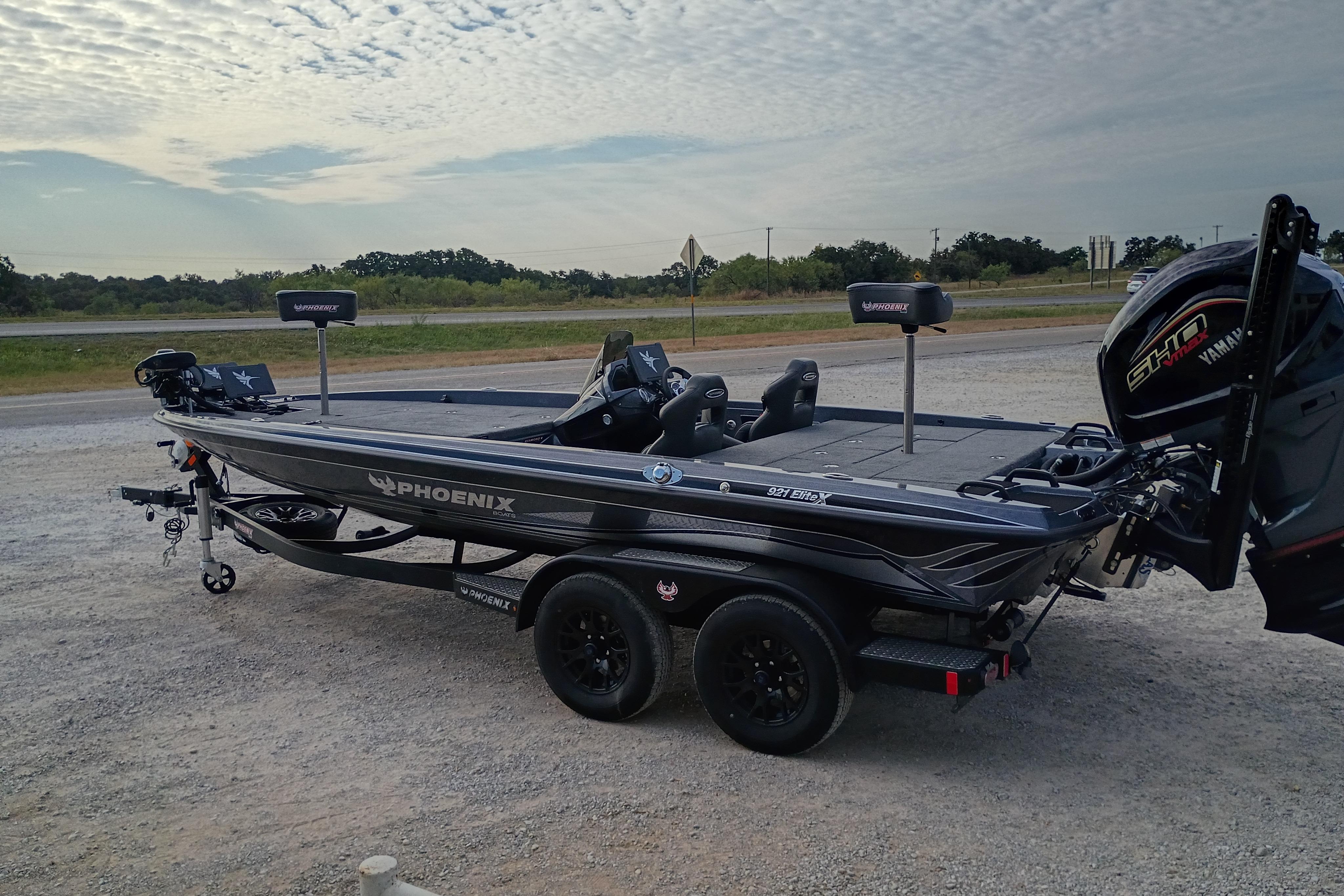2026 Phoenix 921 ELITEX fishing boat on trailer, parked outdoors under cloudy sky.