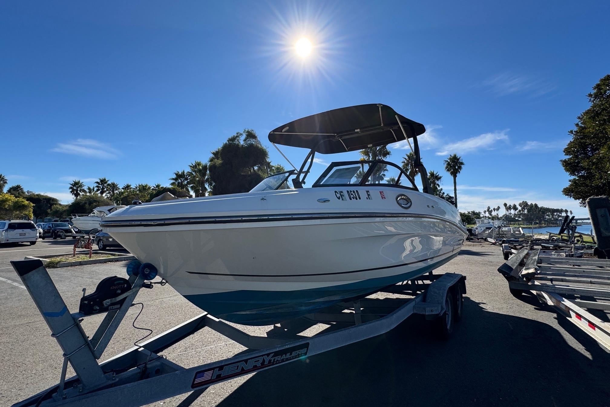 2022 Bayliner VR6 Bowrider OB on trailer under sunny sky, parked near palm trees.