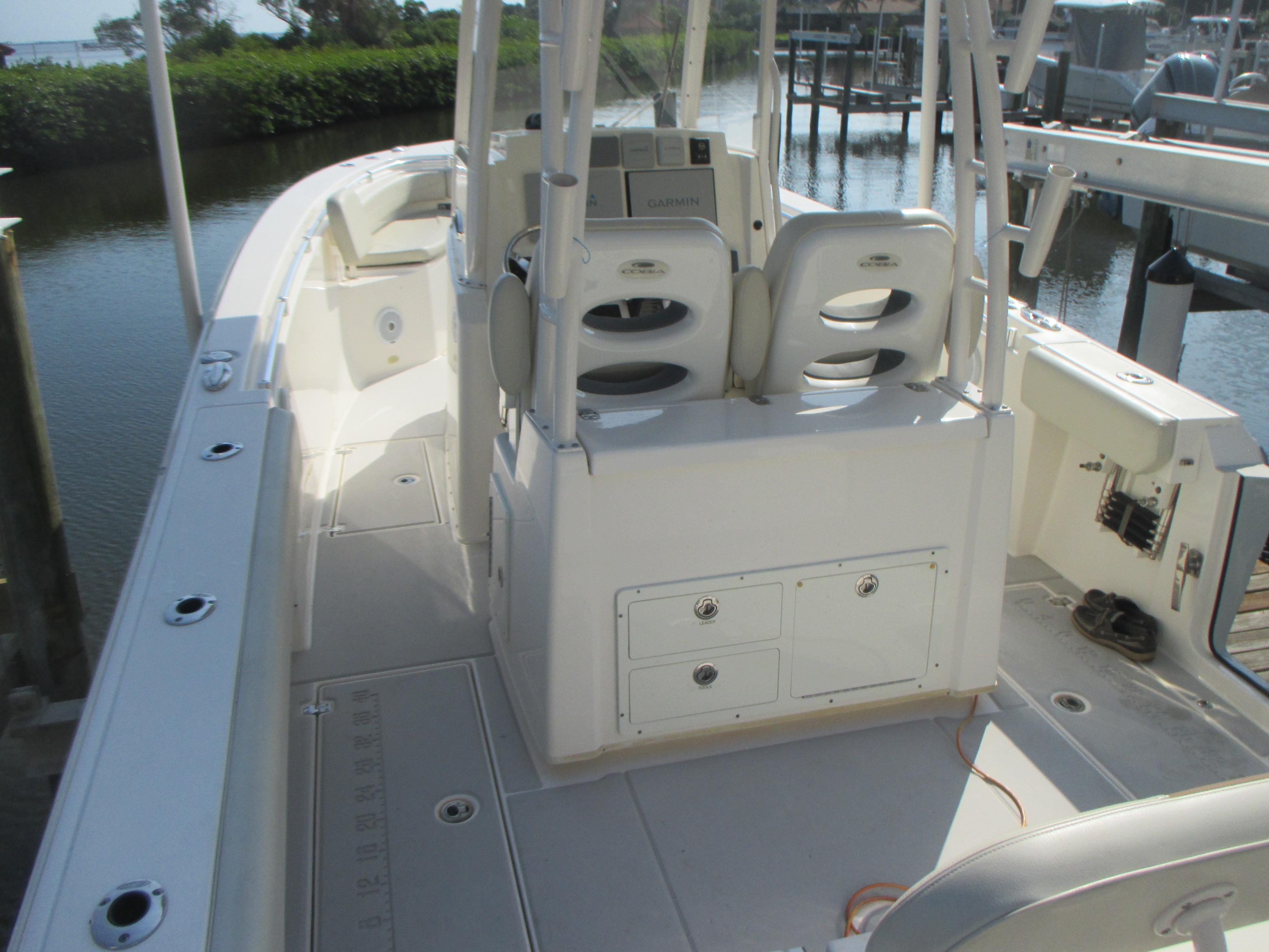 2018 Cobia 301 Center Console boat interior with seating and storage, docked by the water.