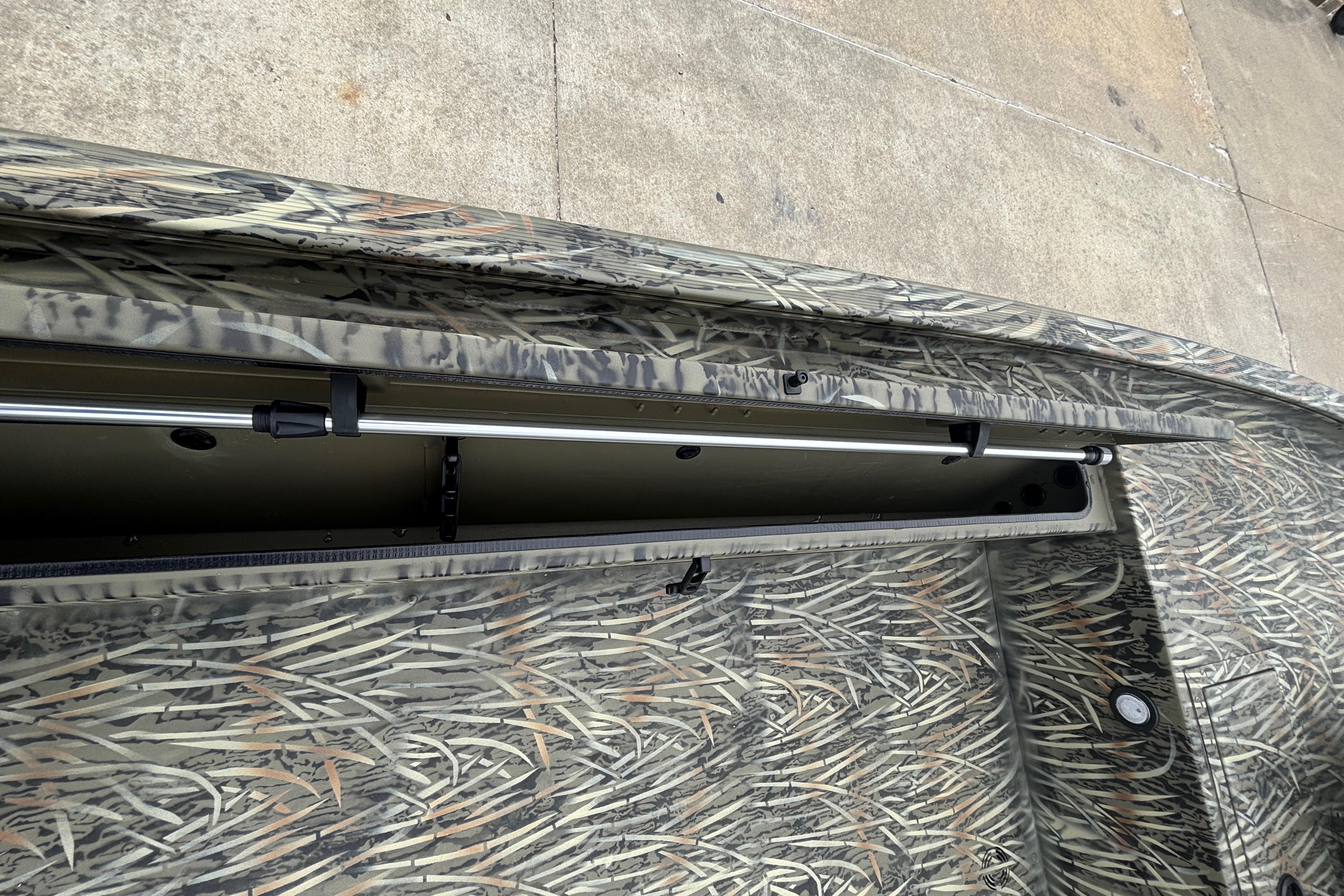 2026 Tracker Grizzly 1654 T Sportsman boat with open storage compartment and camouflage design.