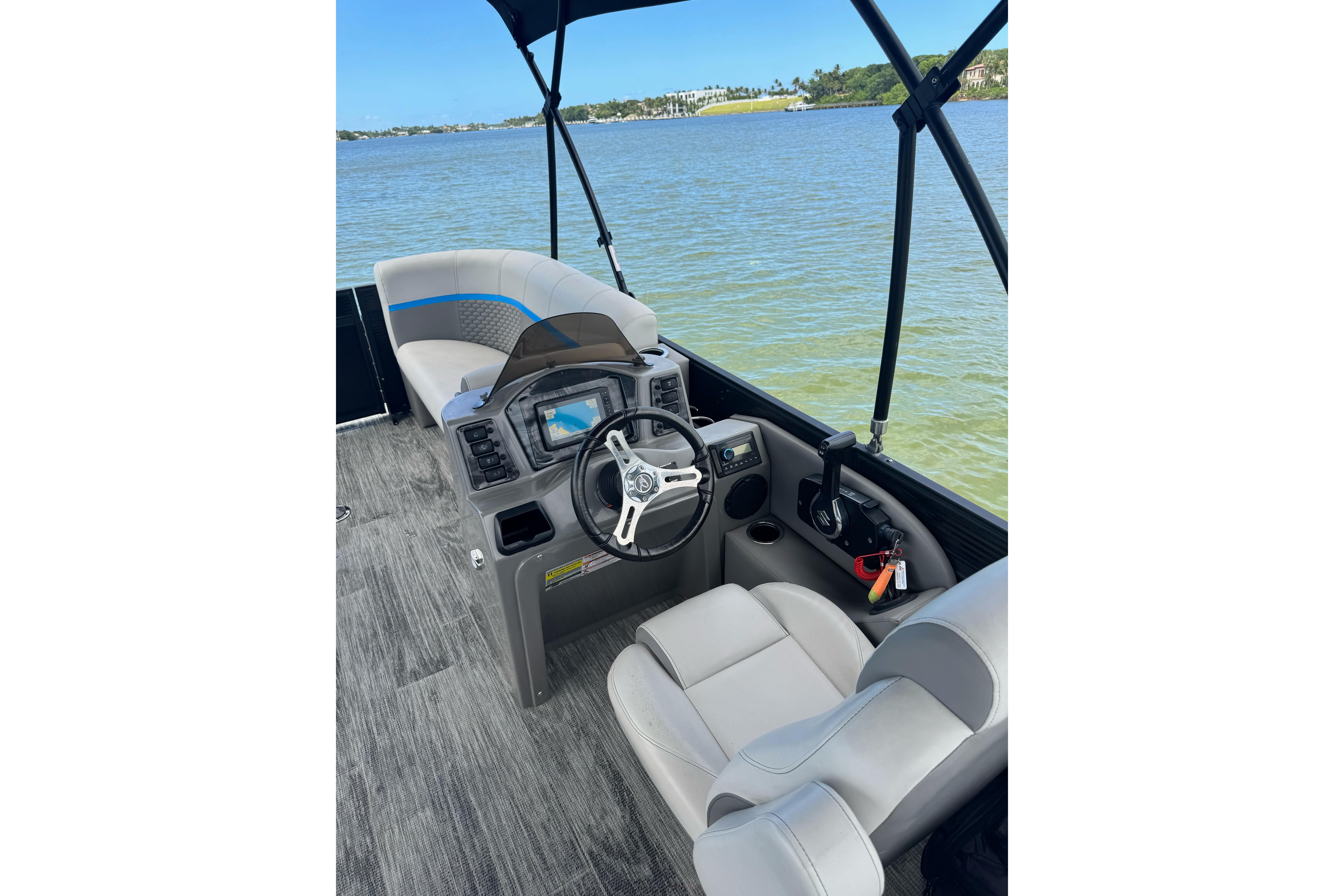Pontoon boat interior with steering console, Qwest Edge 820 CTR, 2022 model, on calm water.