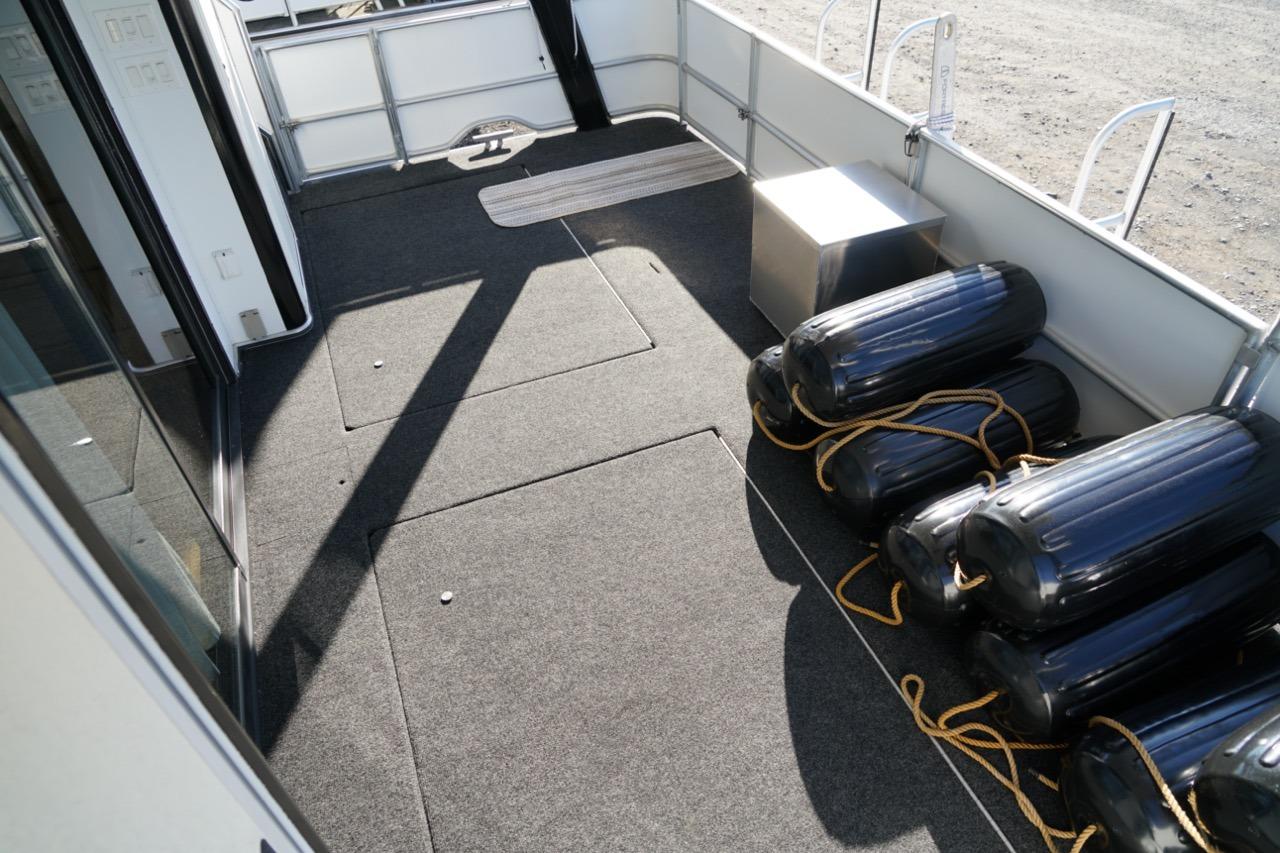 Spacious deck of 2000 Stardust Cruisers houseboat with black fenders and carpet flooring.