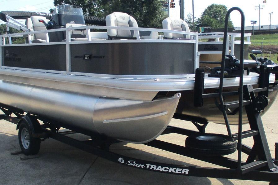 2026 Sun Tracker Bass Buggy 16 XL Select pontoon boat on trailer, parked outdoors.