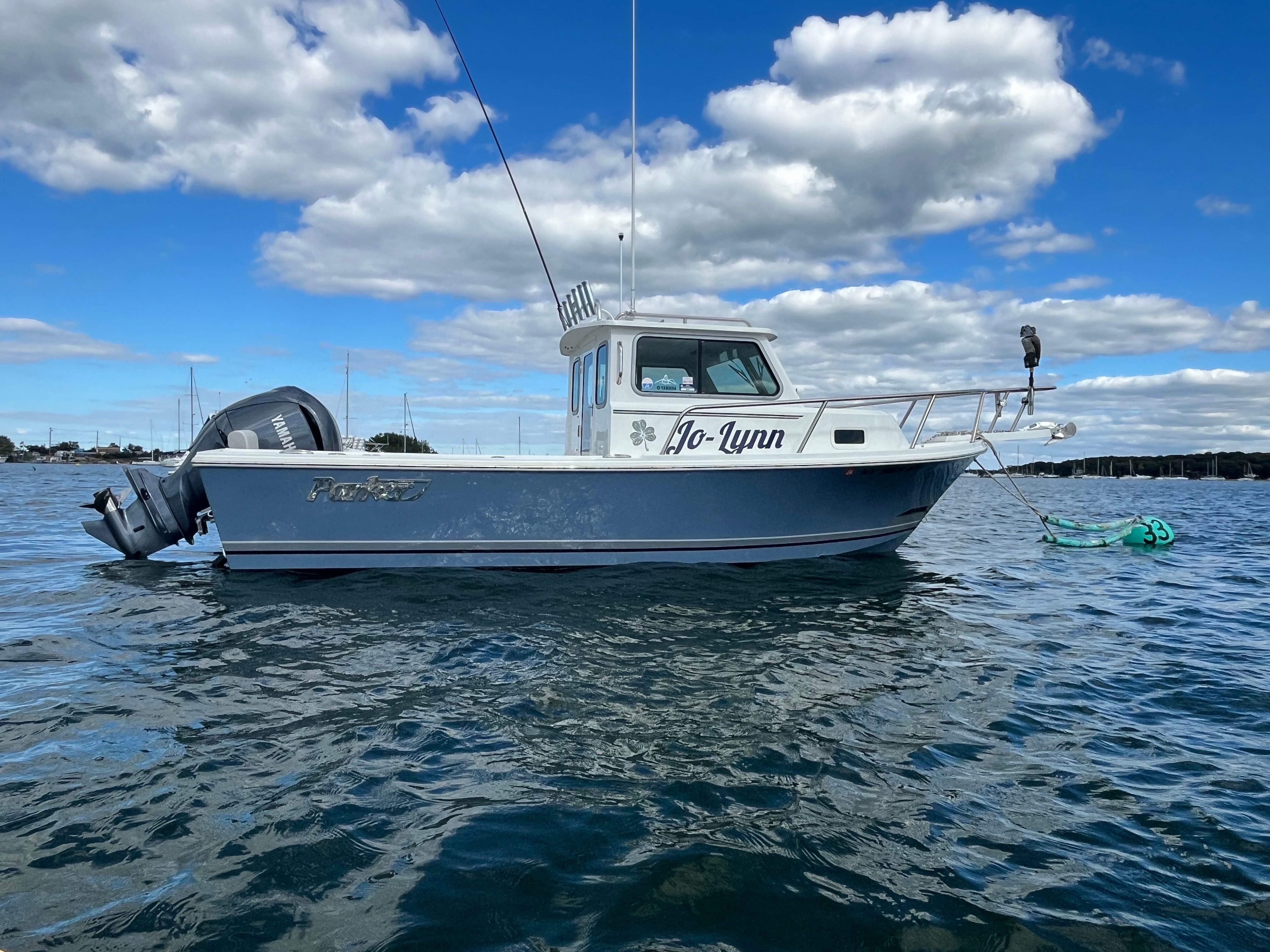 Parker 2021 sport cabin, year 2022, on calm water with blue sky and clouds.