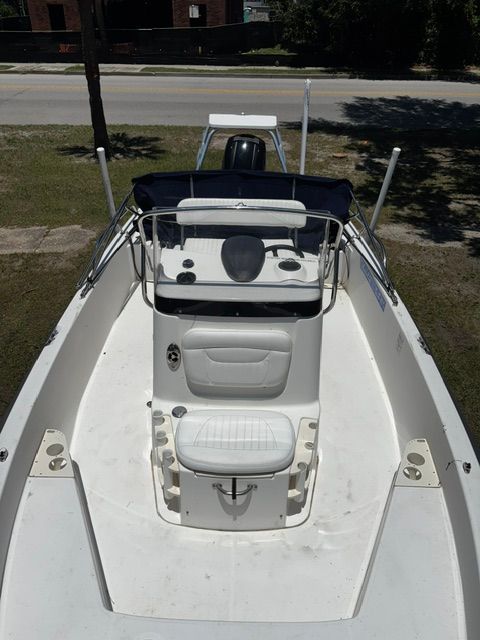 A 2008 Boston Whaler 200 Dauntless with a white deck and helm, parked on grass.