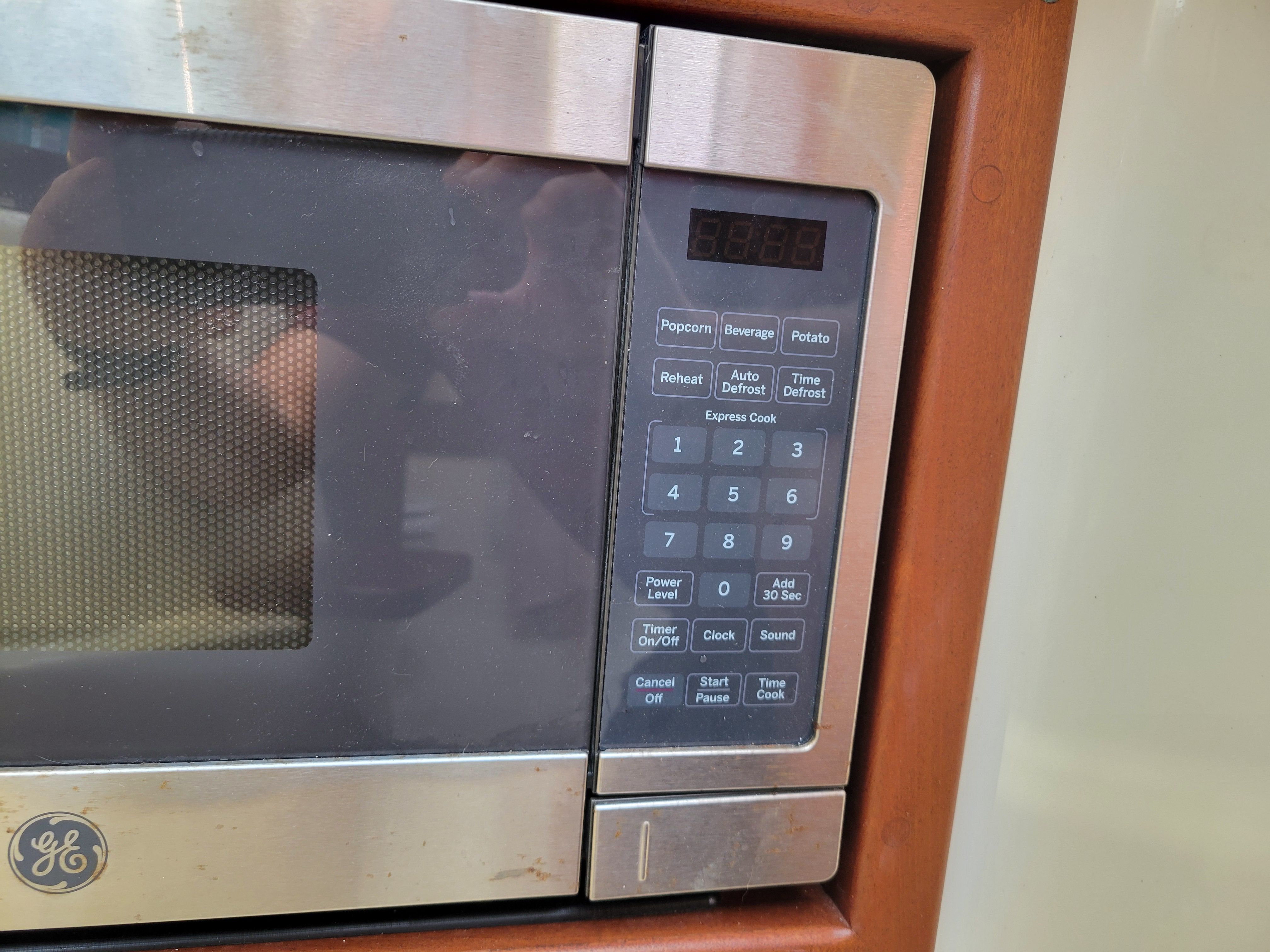 GE microwave with digital control panel in wooden frame.