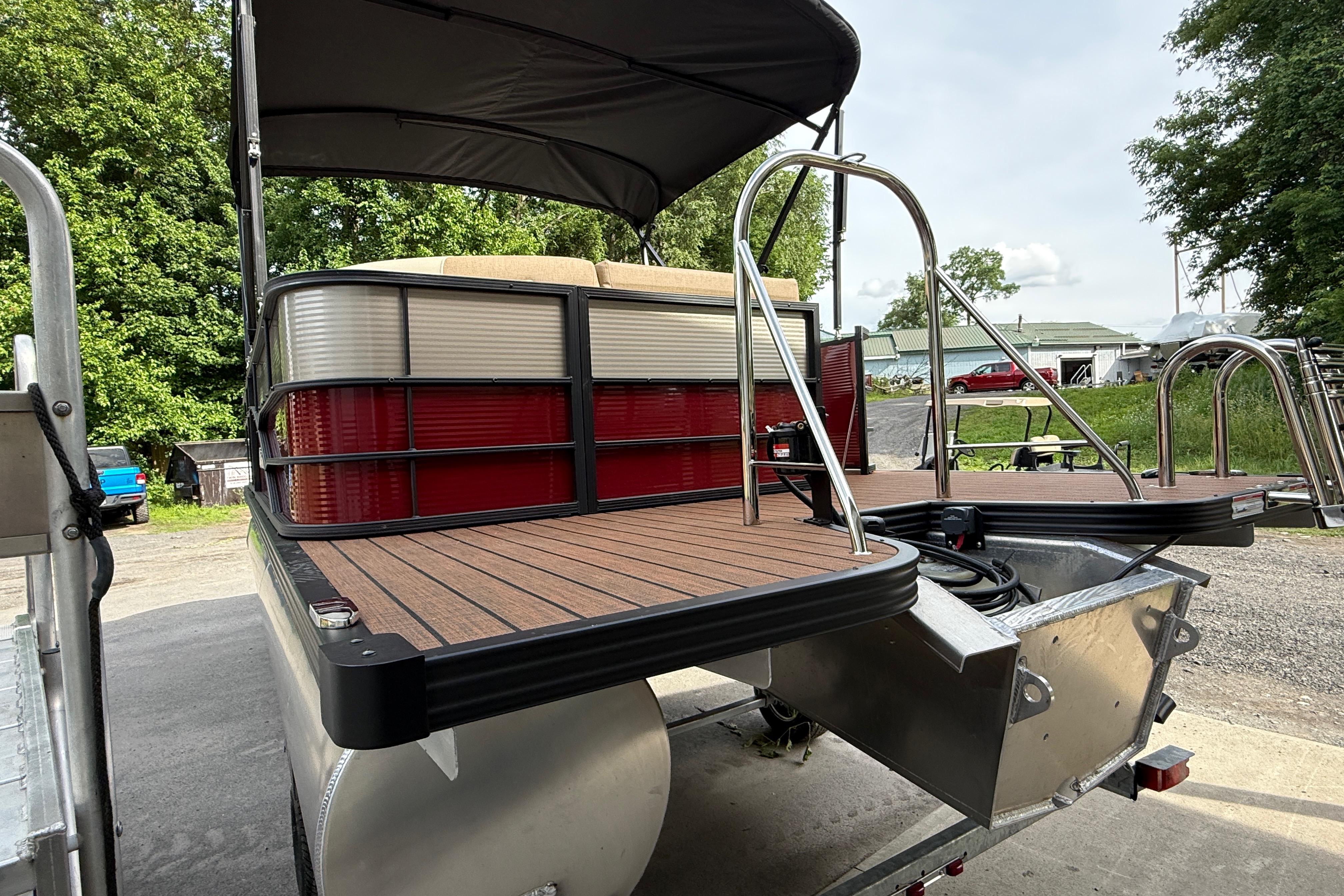 2027 Manitou 21 Aurora LE pontoon boat with sleek deck and canopy, parked outdoors.