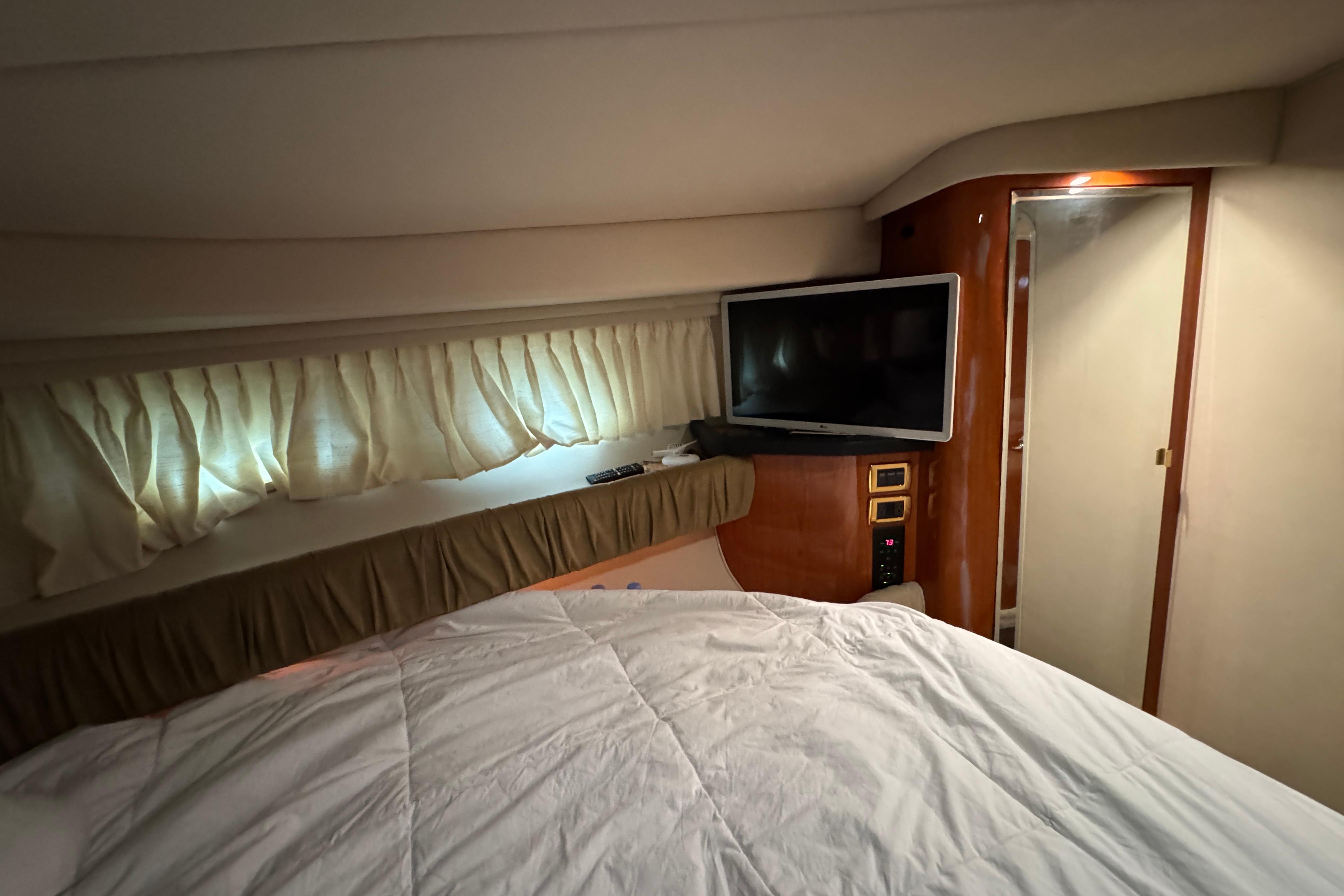 Interior cabin of 2001 Sea Ray 380 Sundancer with bed, TV, and curtains.