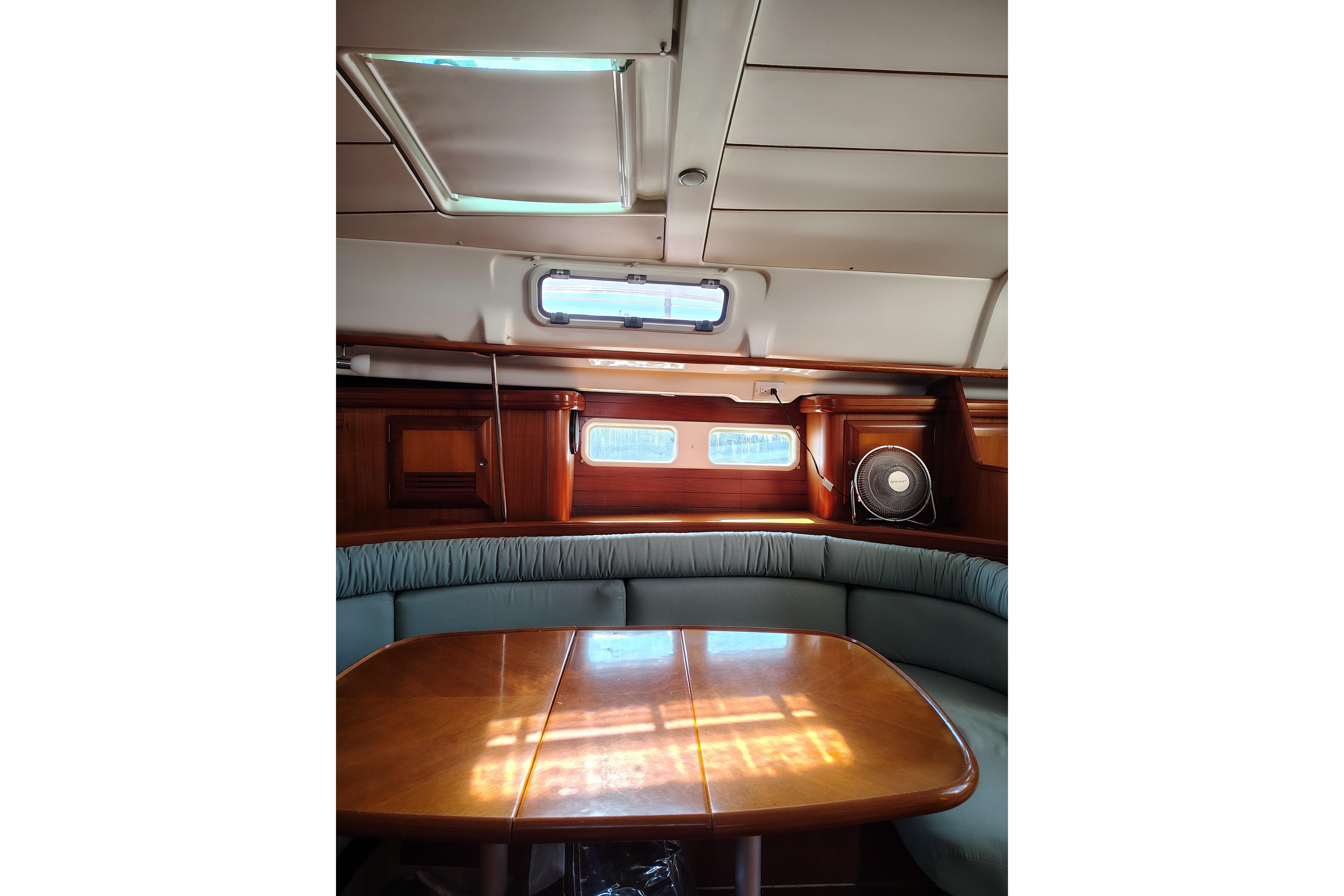 Interior of 2001 Beneteau Oceanis 411 sailboat with wooden table and cushioned seating.