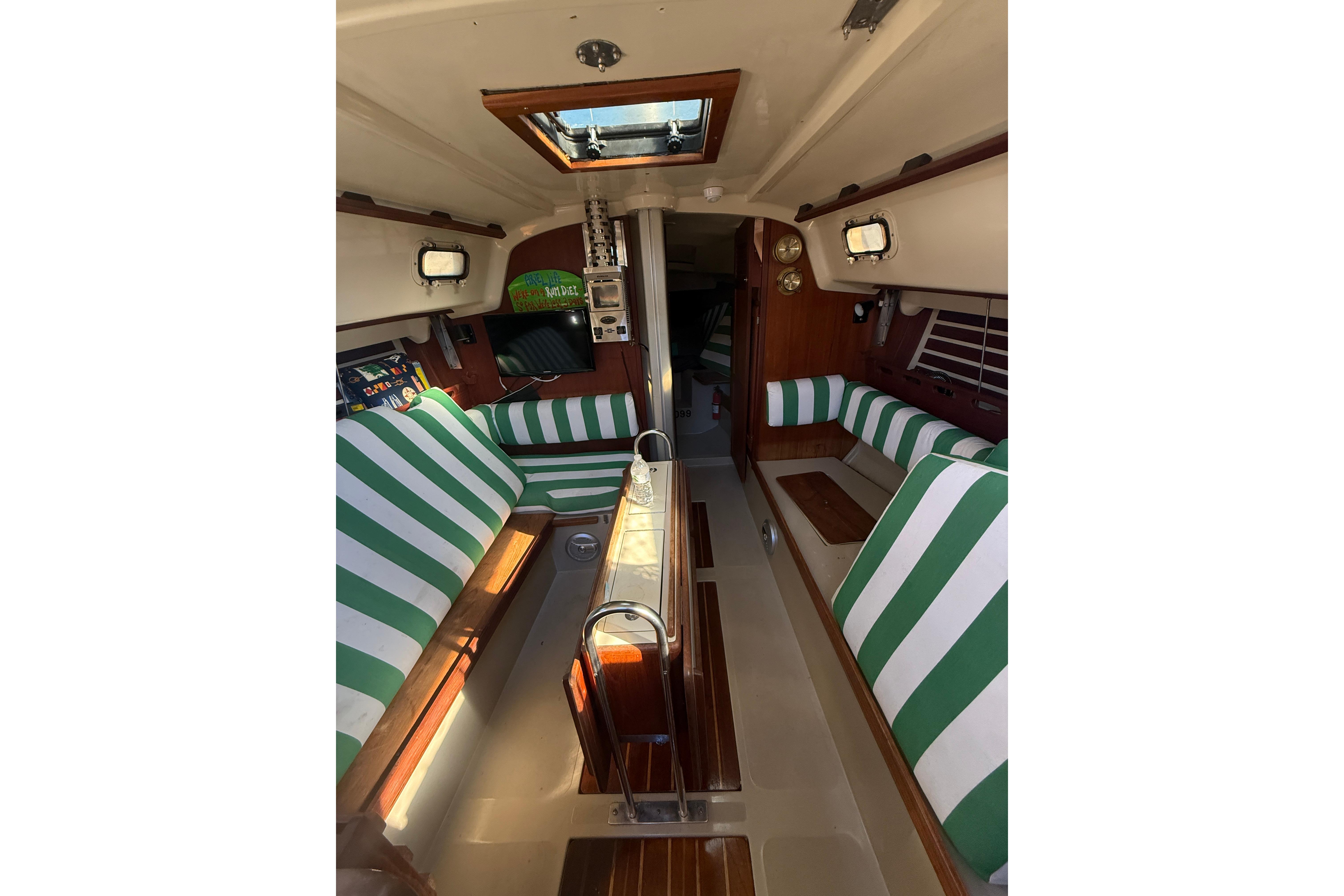 Interior of a 1983 O'Day 34 sailboat with green-striped seating and wood accents.