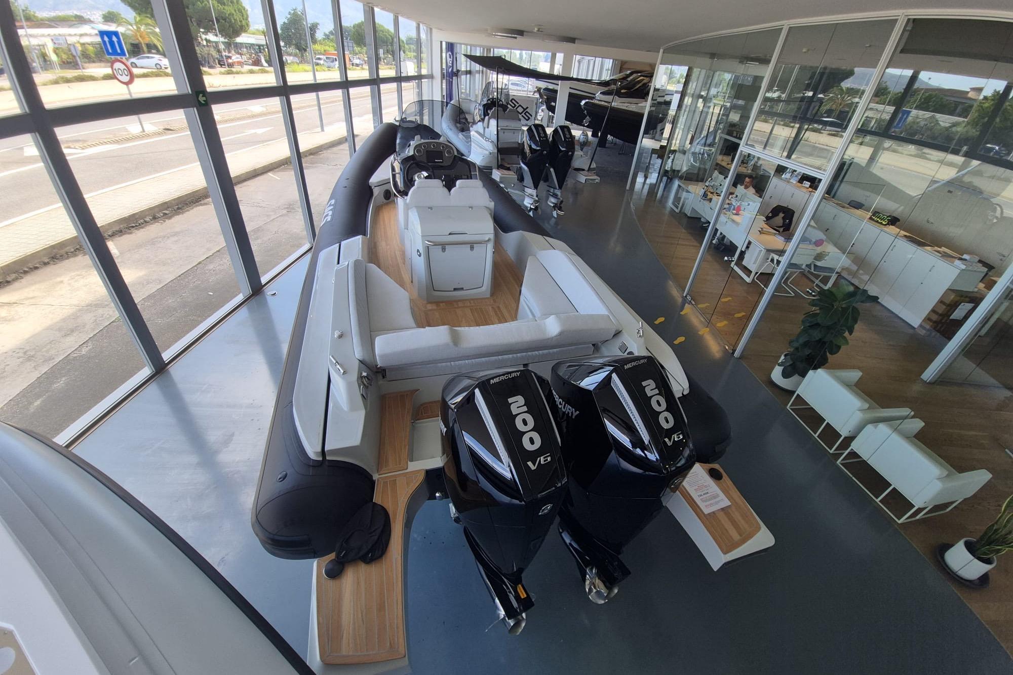 2026 SACS Strider 900 boat with dual Mercury 200 V6 engines in a showroom.