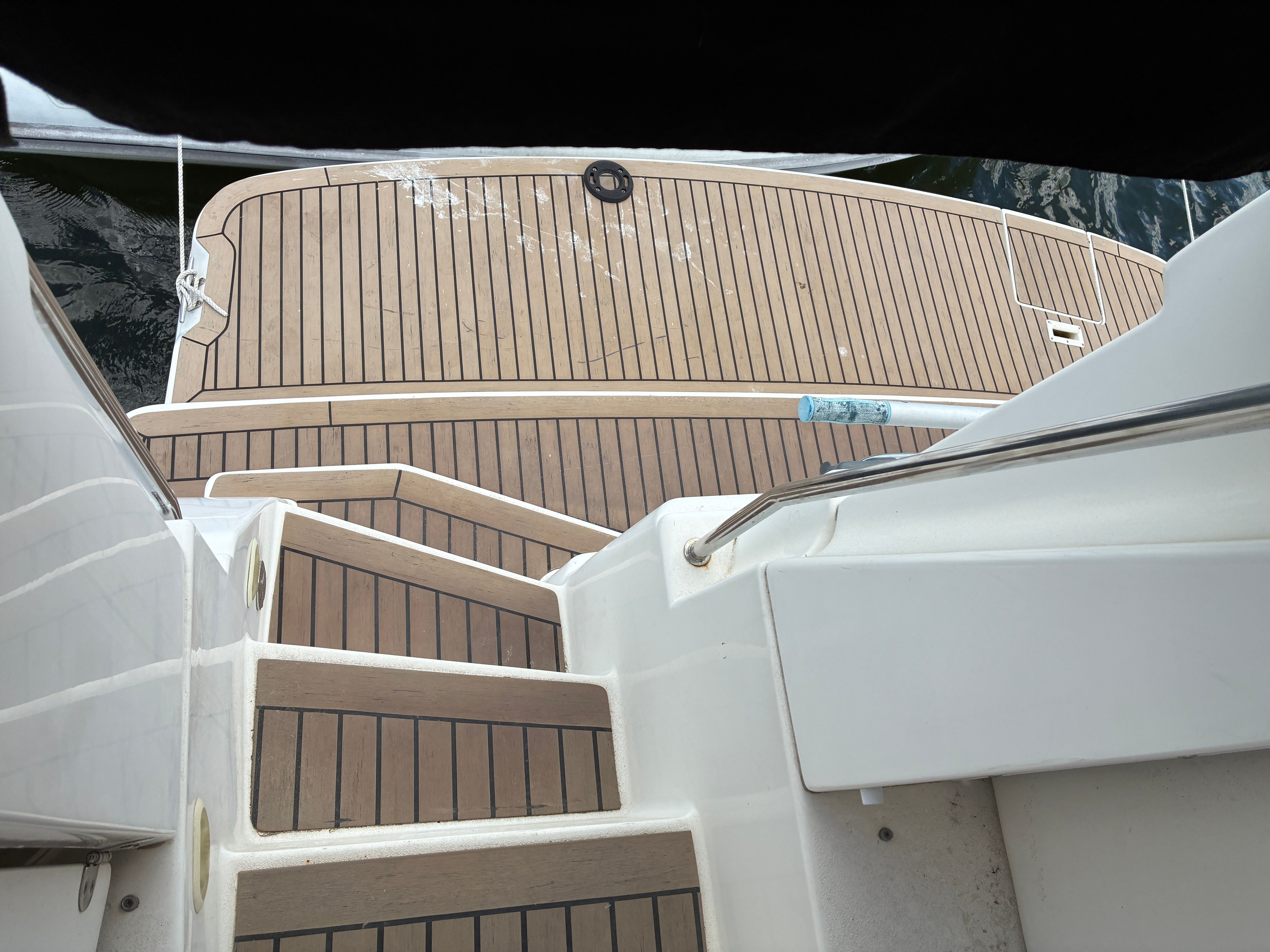 The stairs of a 2001 Silverton 392 Motor Yacht lead to a deck with wood-like finish.
