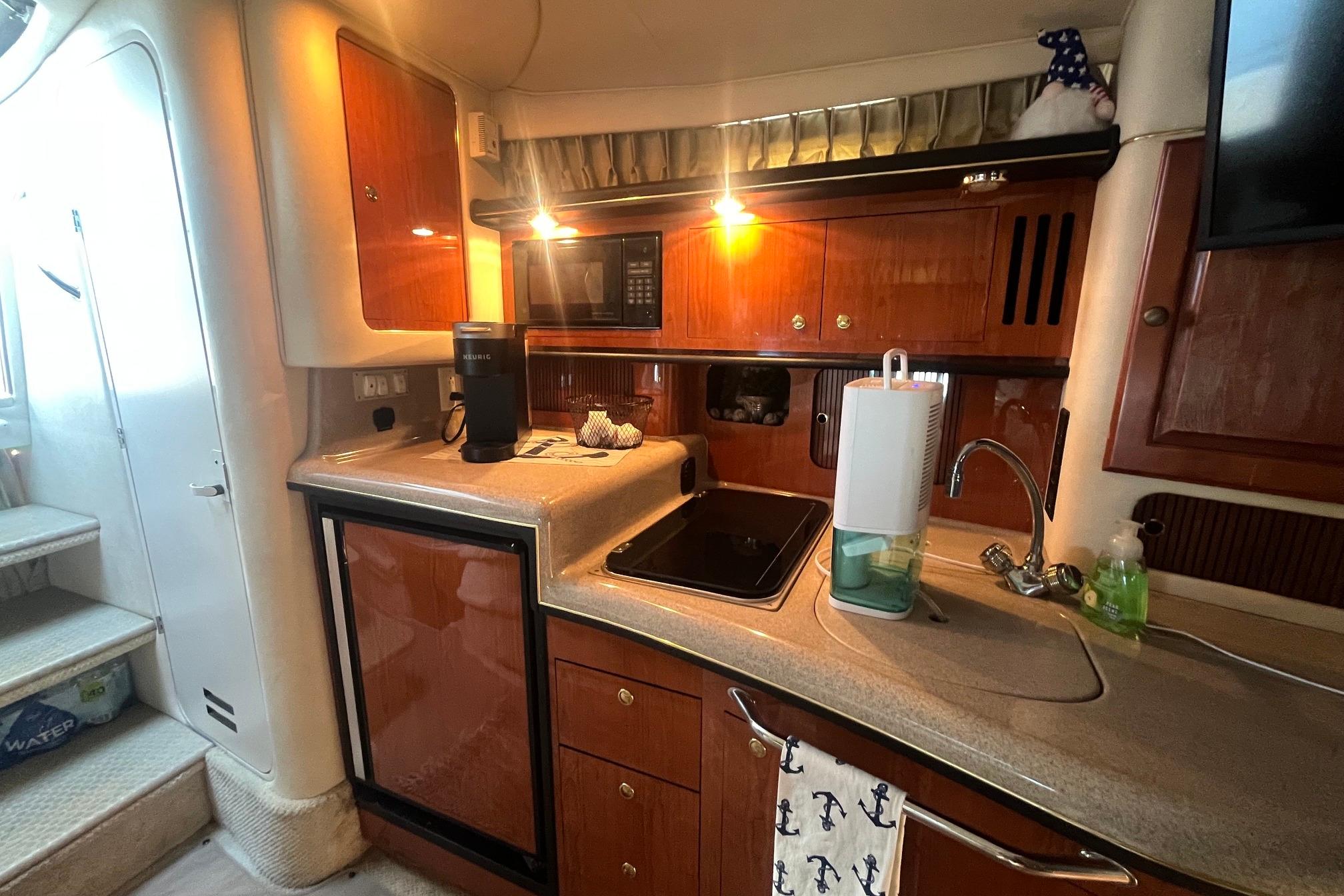 Interior of 2001 Sea Ray 340 Sundancer yacht kitchen with wooden cabinets and modern appliances.