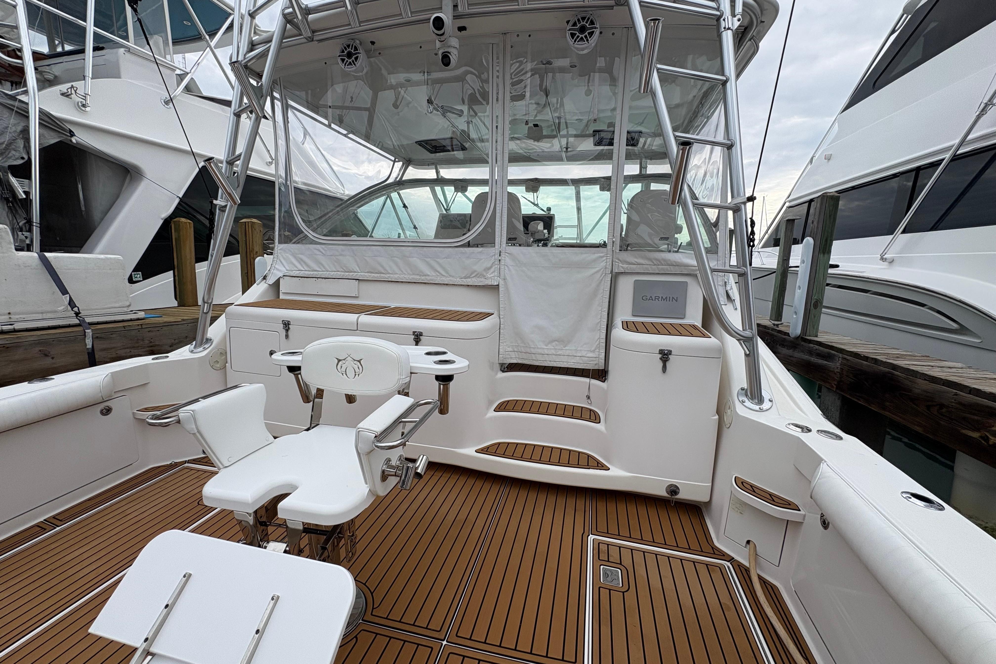 2004 Cabo 40 Hardtop Express boat with teak deck and fishing chair in marina.