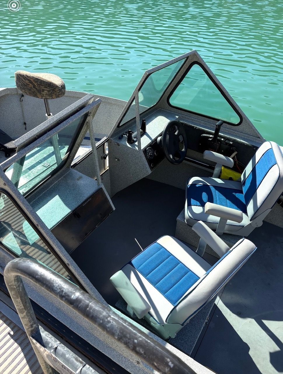 The image shows the cockpit of a 2002 Stryker Rogue boat with blue seats.