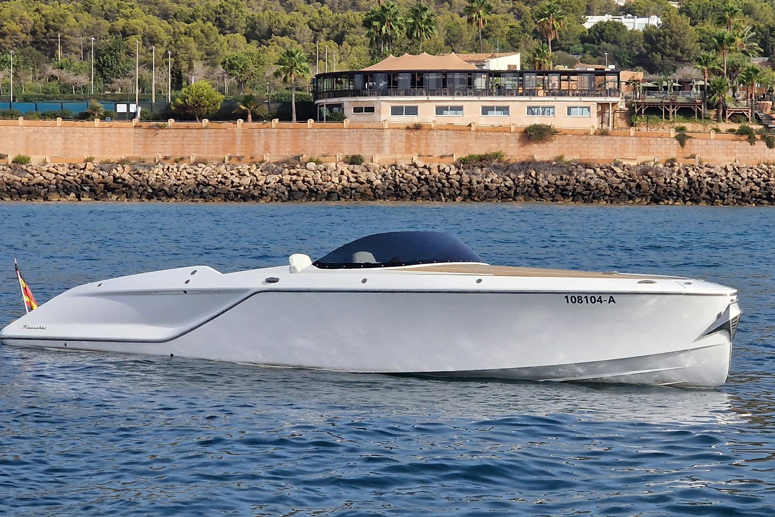 2021 Frauscher 858 Fantom luxury boat on calm water near a scenic shoreline.