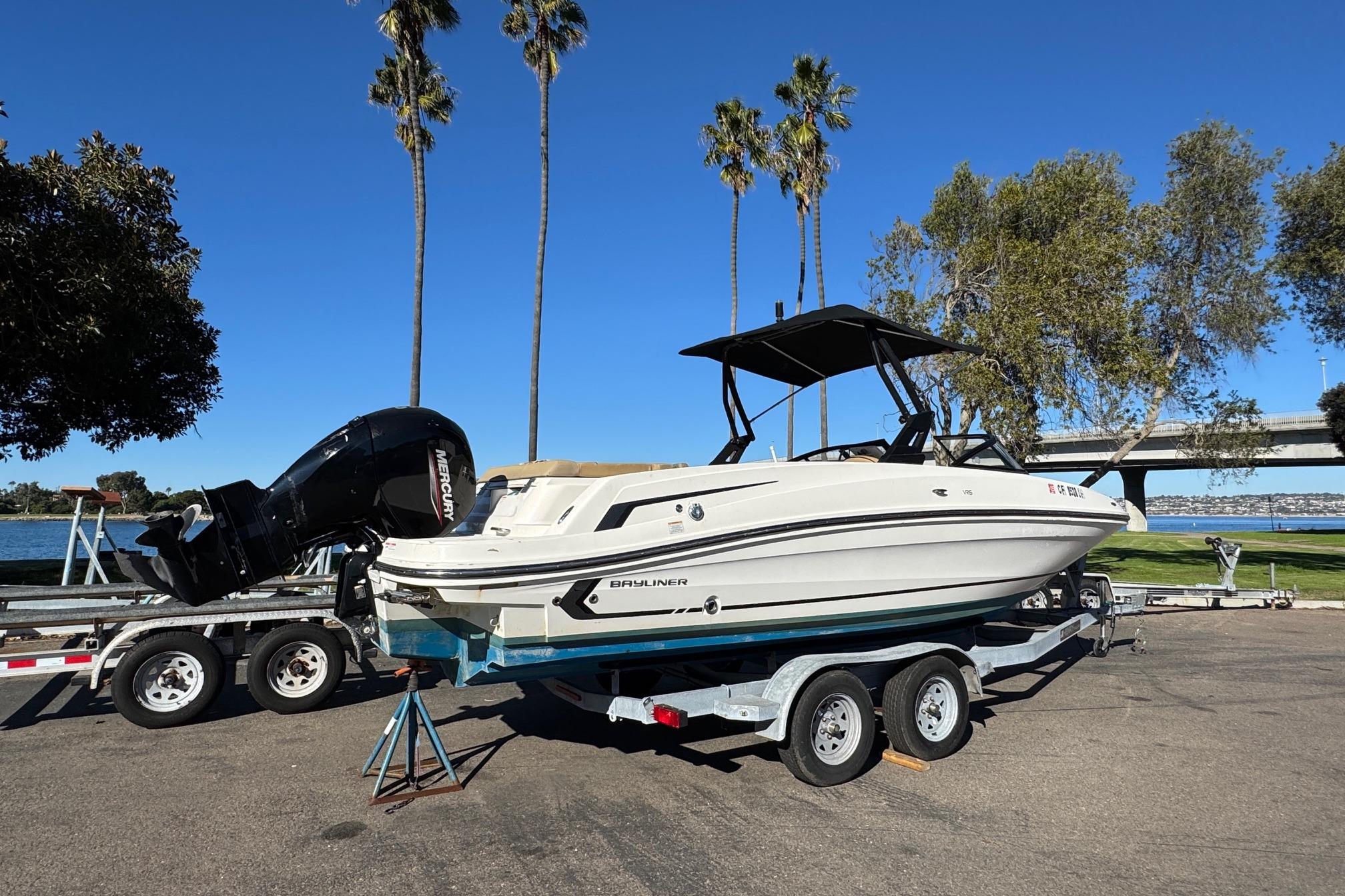 2022 Bayliner VR6 Bowrider OB on trailer, parked near waterfront with palm trees.