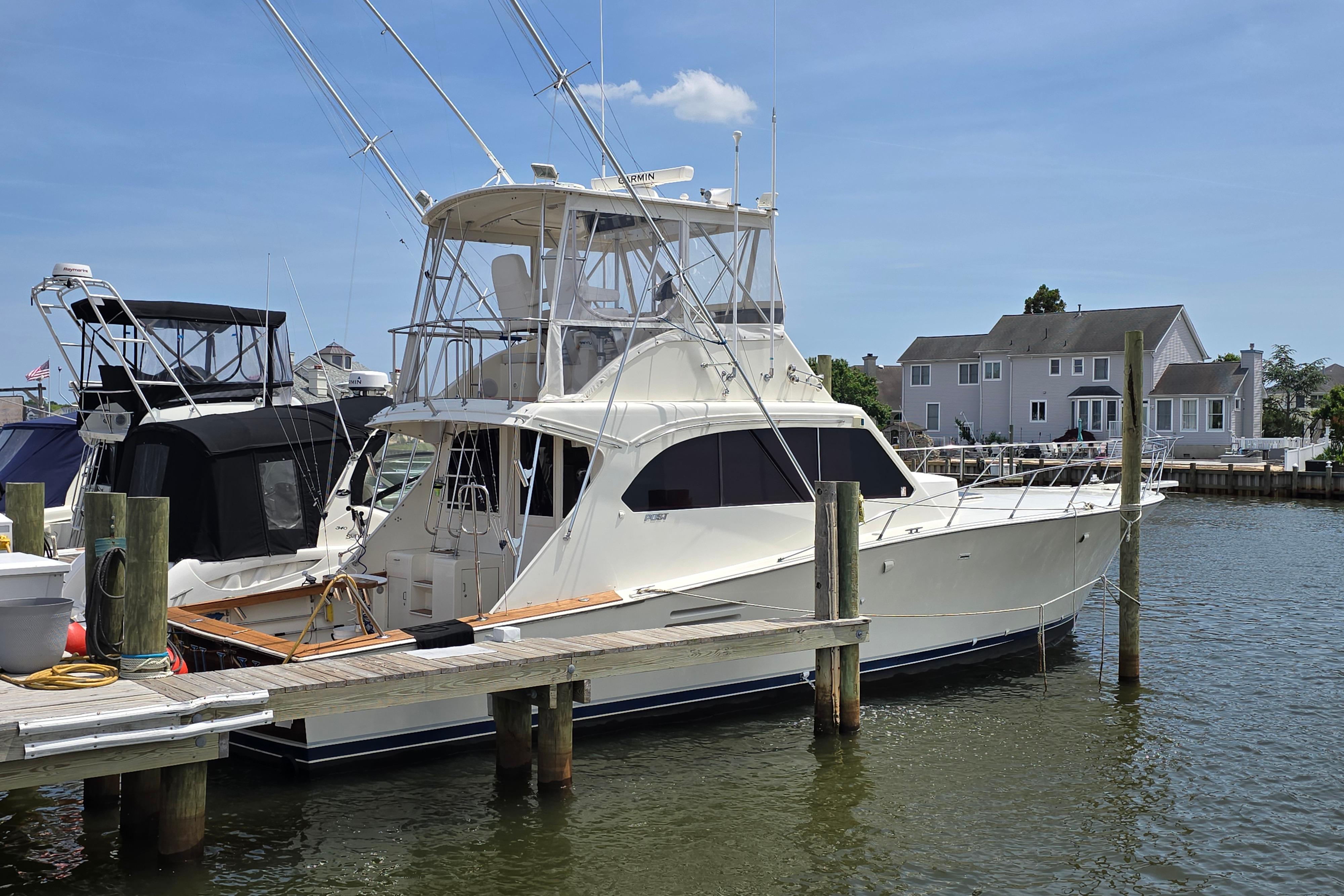 1988 Post 46 Convertible yacht docked at marina, clear sky, waterfront homes in background.