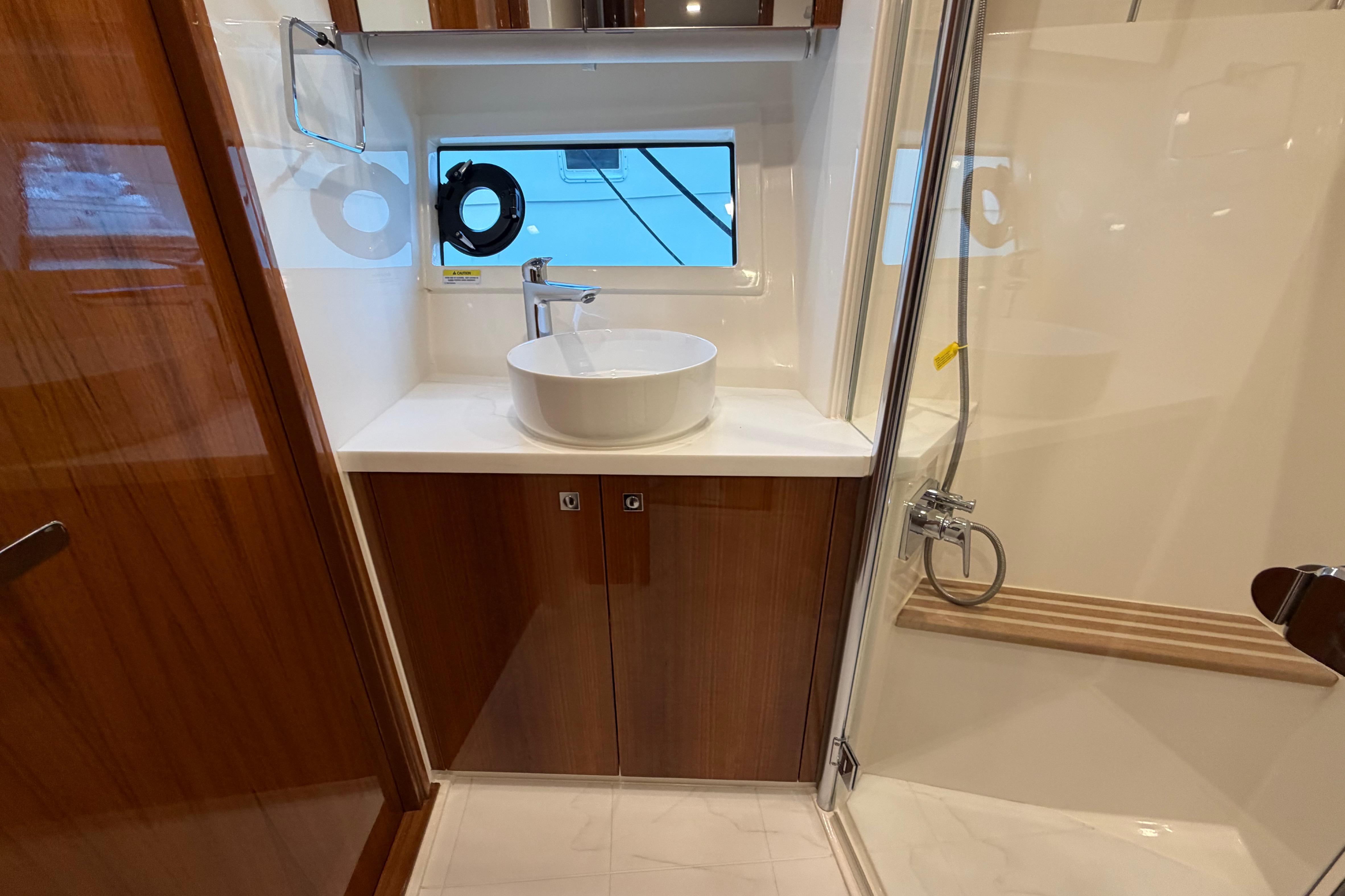 Luxurious bathroom in 2023 Riviera 645 SUV yacht with modern sink and shower.