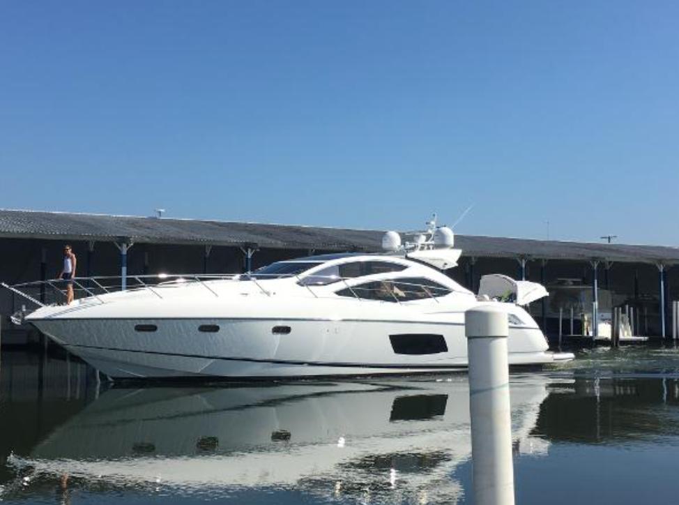 2013 Sunseeker Predator 64 yacht docked in a marina under clear blue skies.
